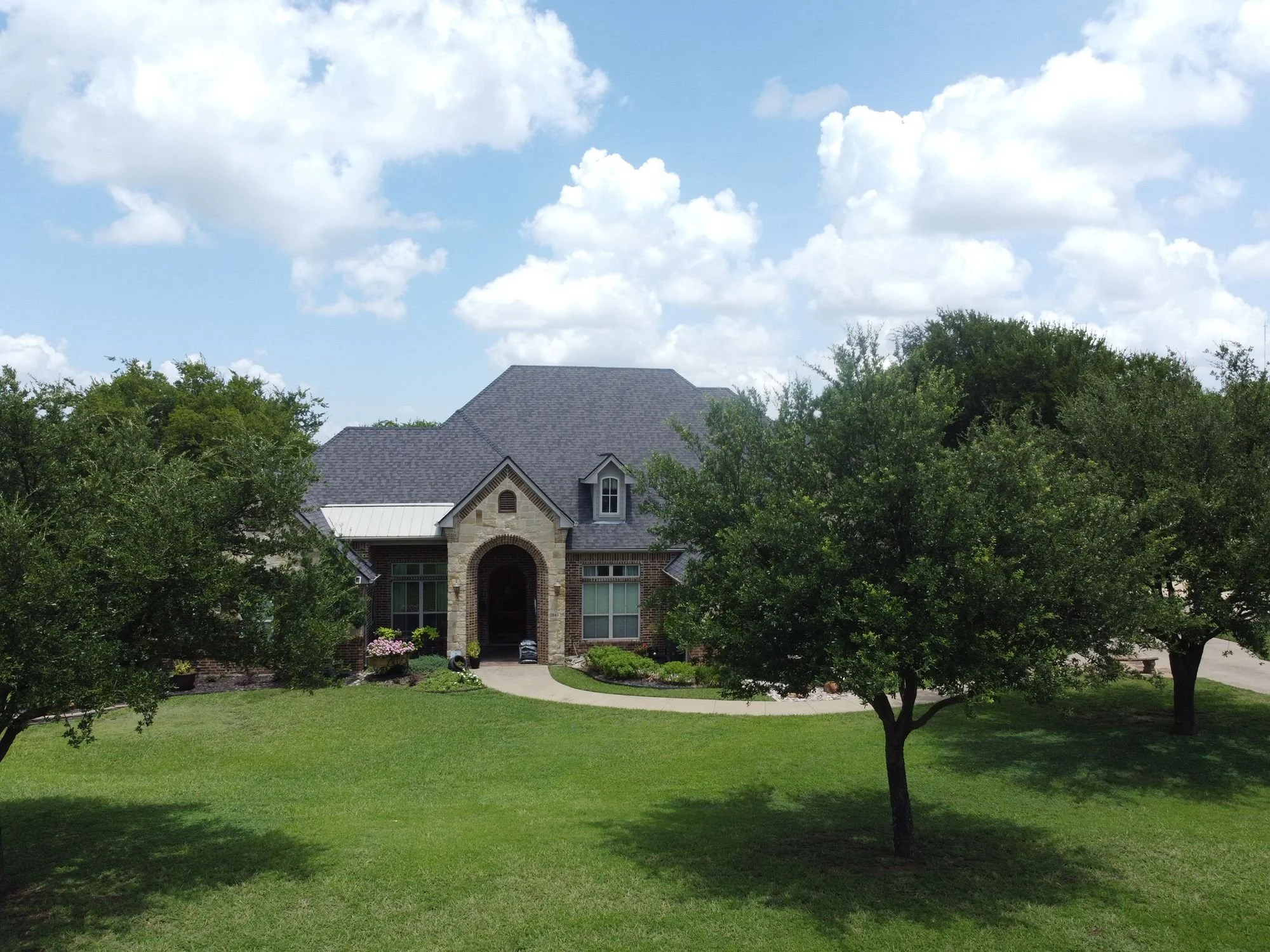 Large stone home with a new shingle roof by Christian Brothers Roofing in North Texas