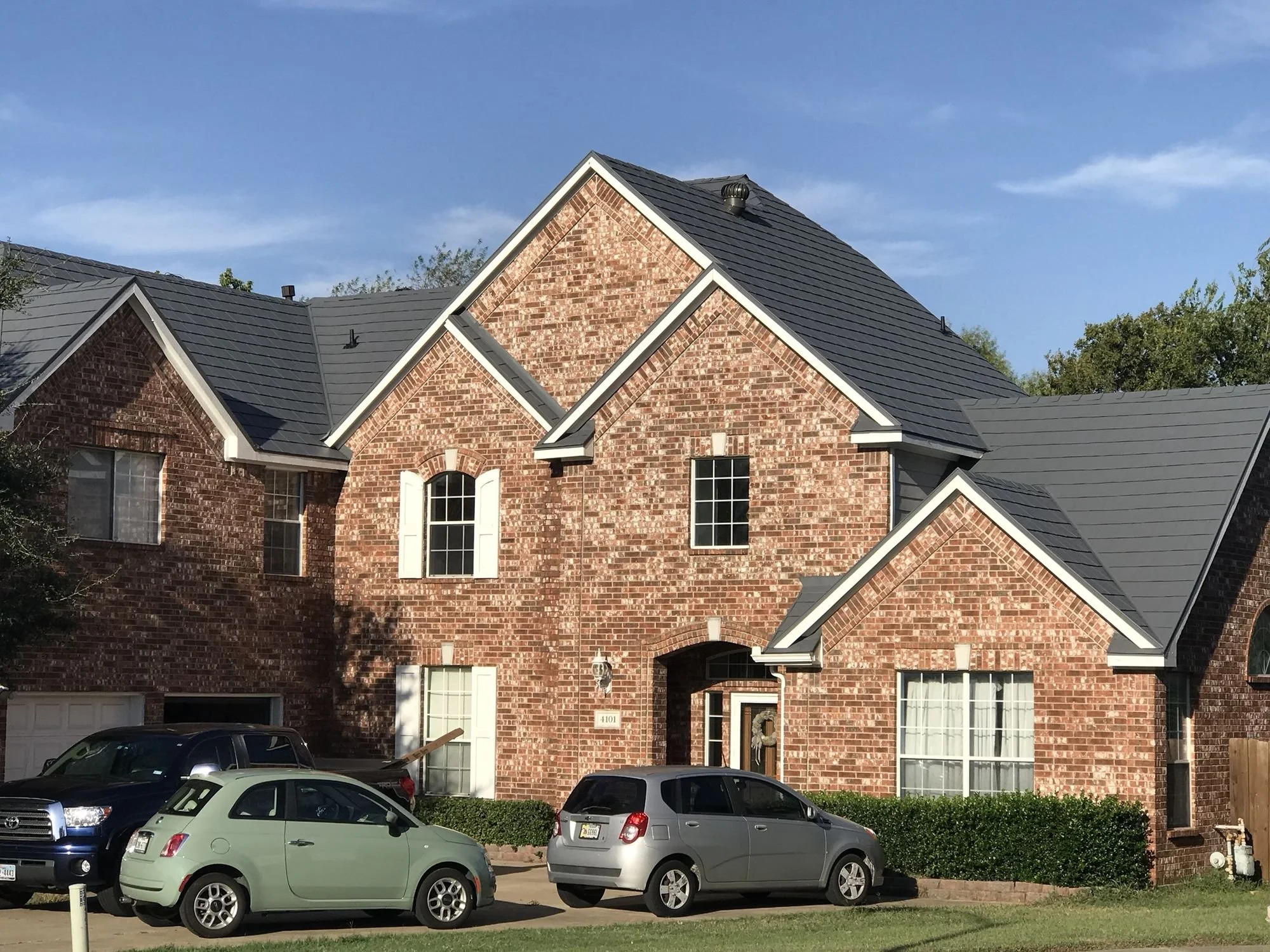 Two-story brick home with a new shingle roof by Christian Brothers Roofing in North Texas