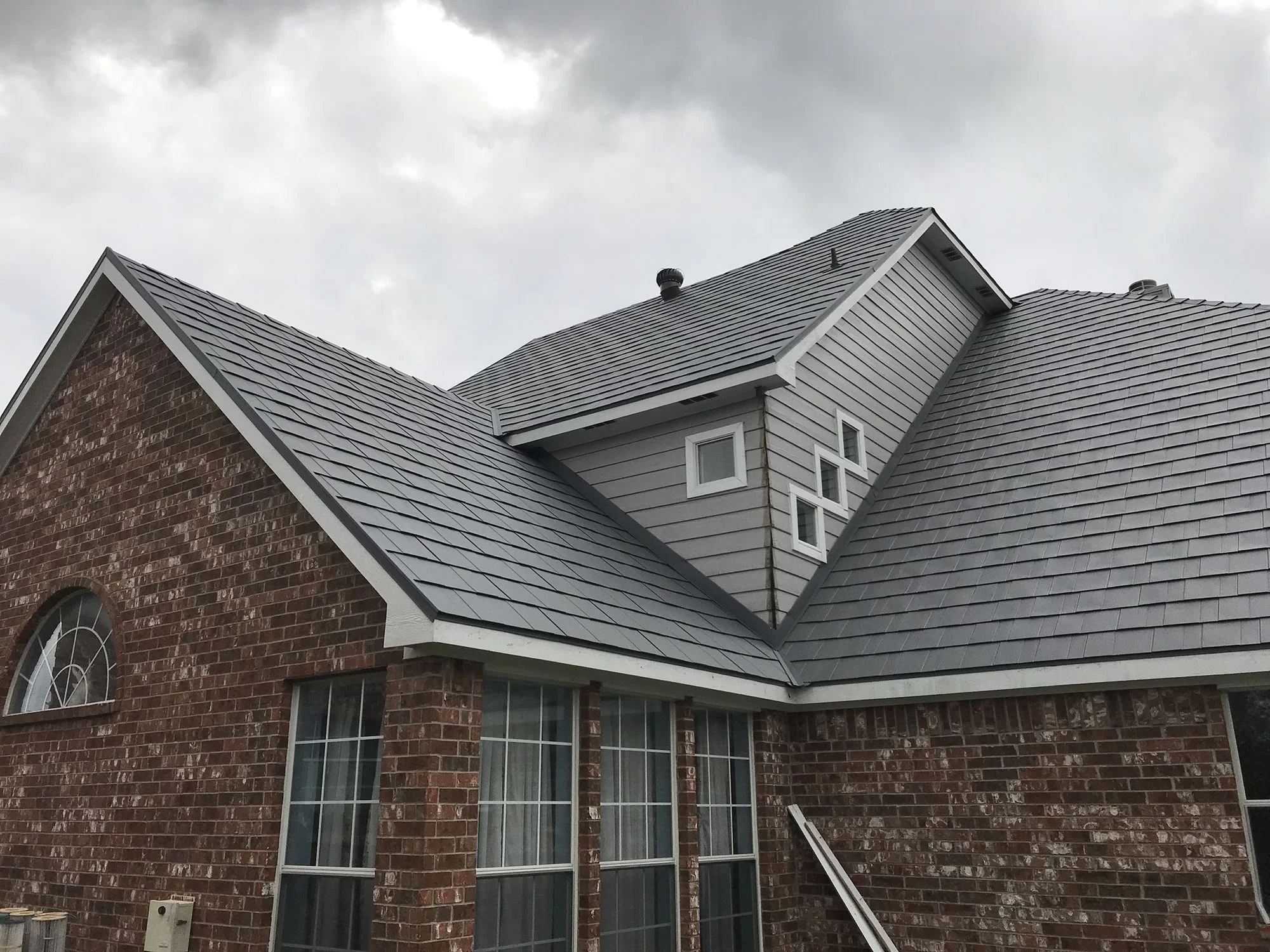 Brick home with a new gray shingle roof by Christian Brothers Roofing in North Texas