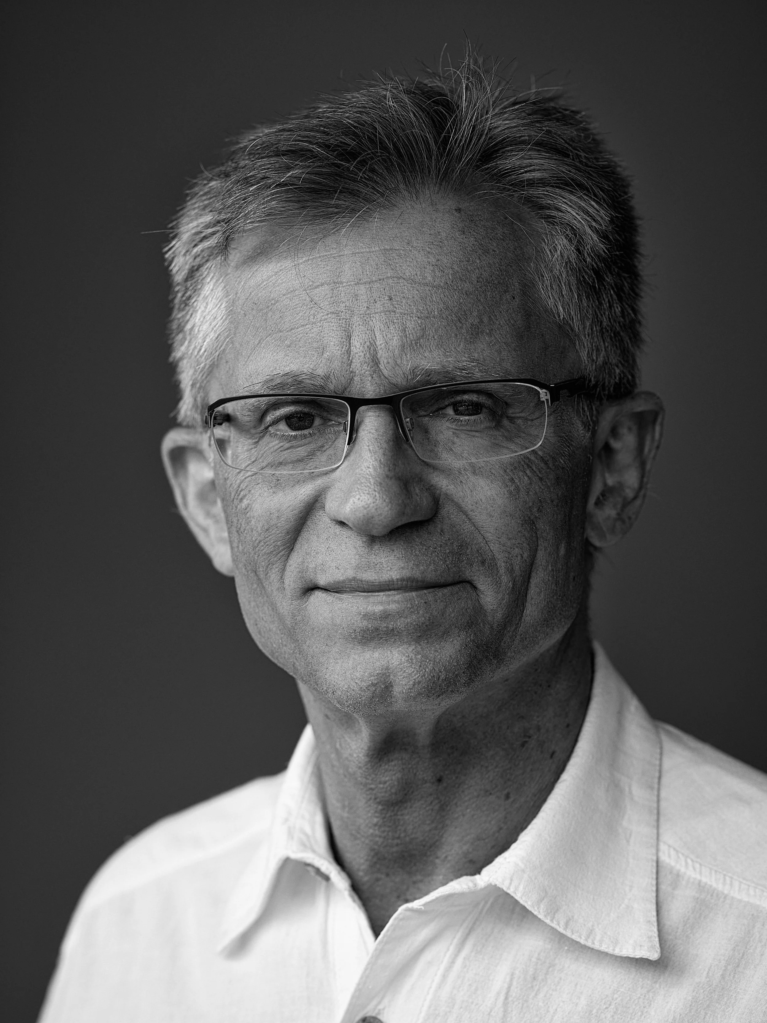 Black and white close-up portrait of an elderly man wearing glasses and a white collared shirt.