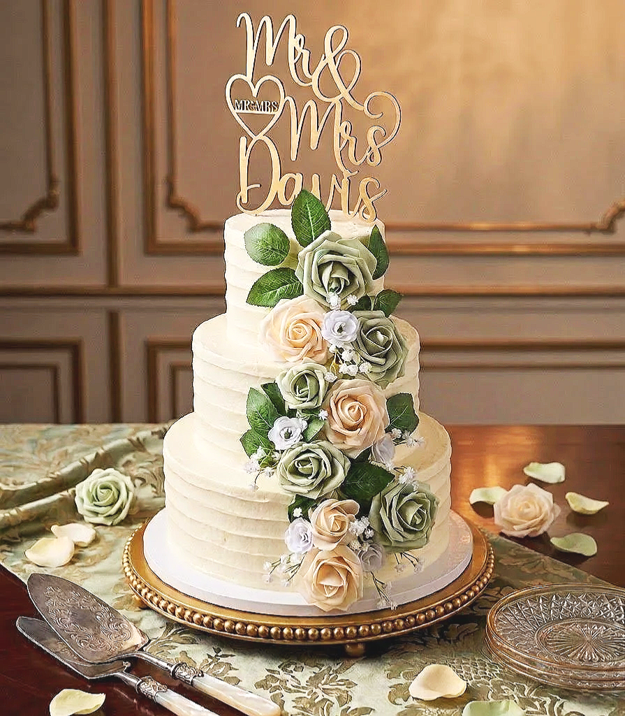 A three-tier wedding cake decorated with cascading roses and greenery.