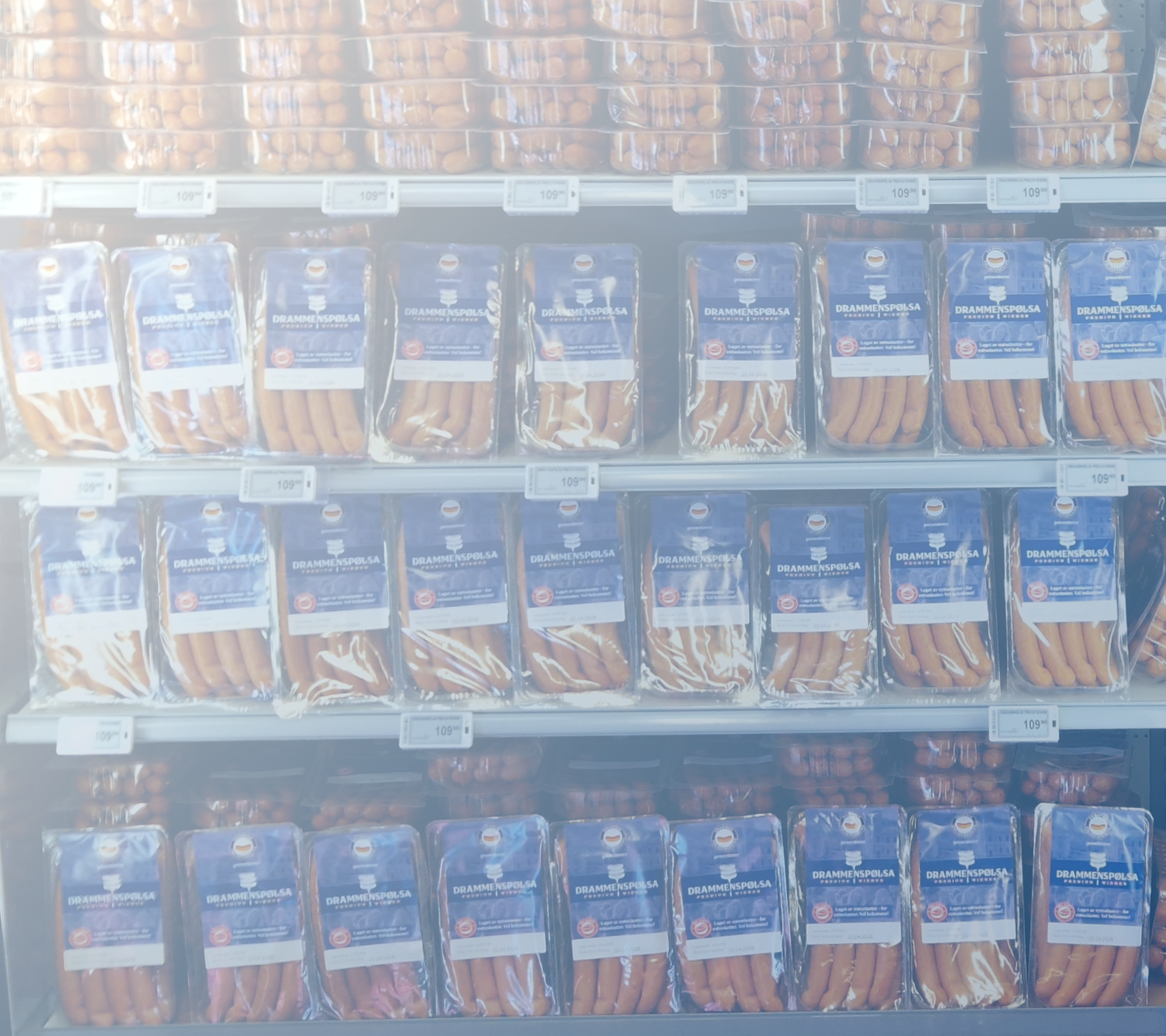 Frosne pølser på kjøleskapsregal i en dagligvarebutikk, pakket i blå og klare plastemballasjer.