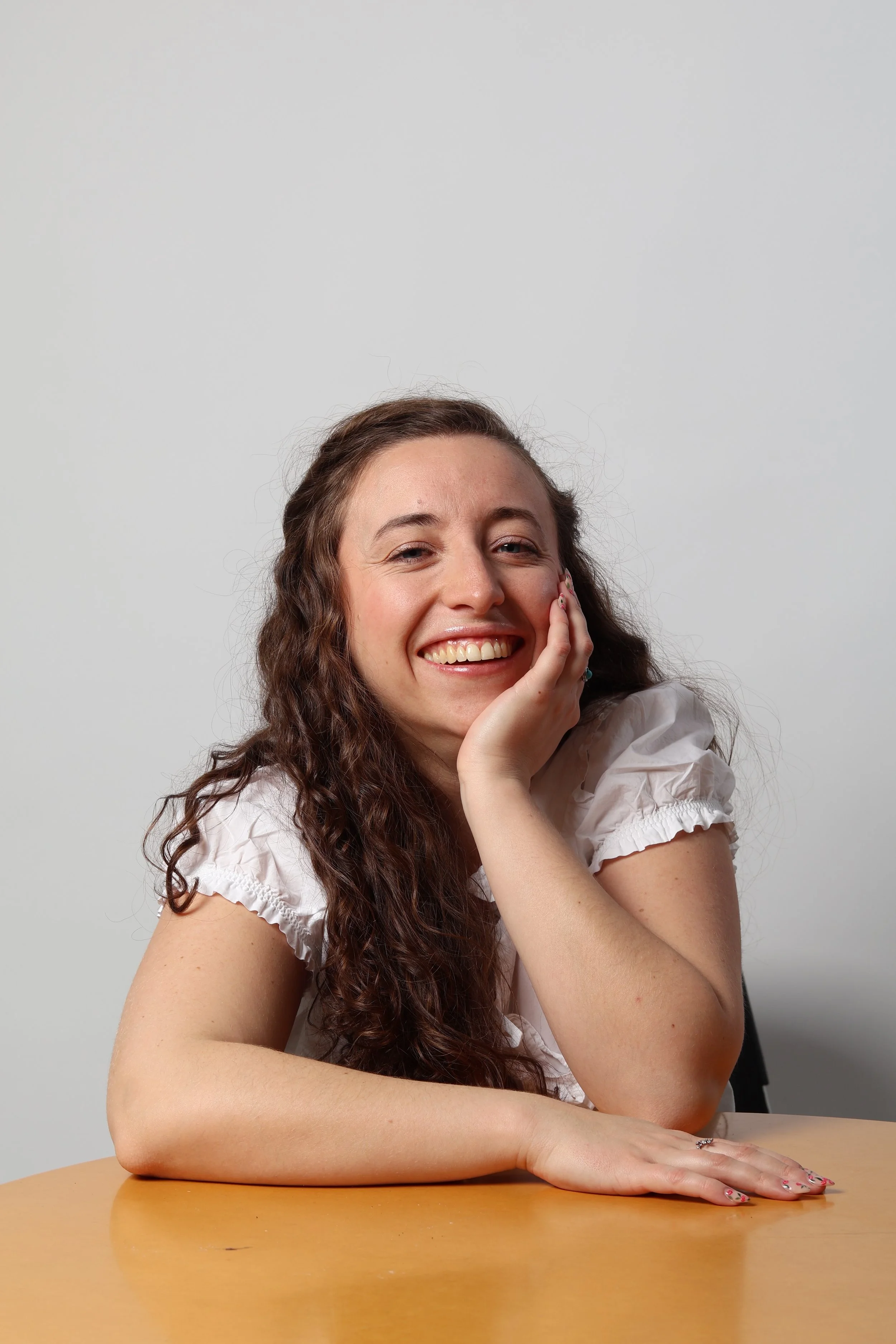 Hannah Smiling at the camera with a hand on her cheek