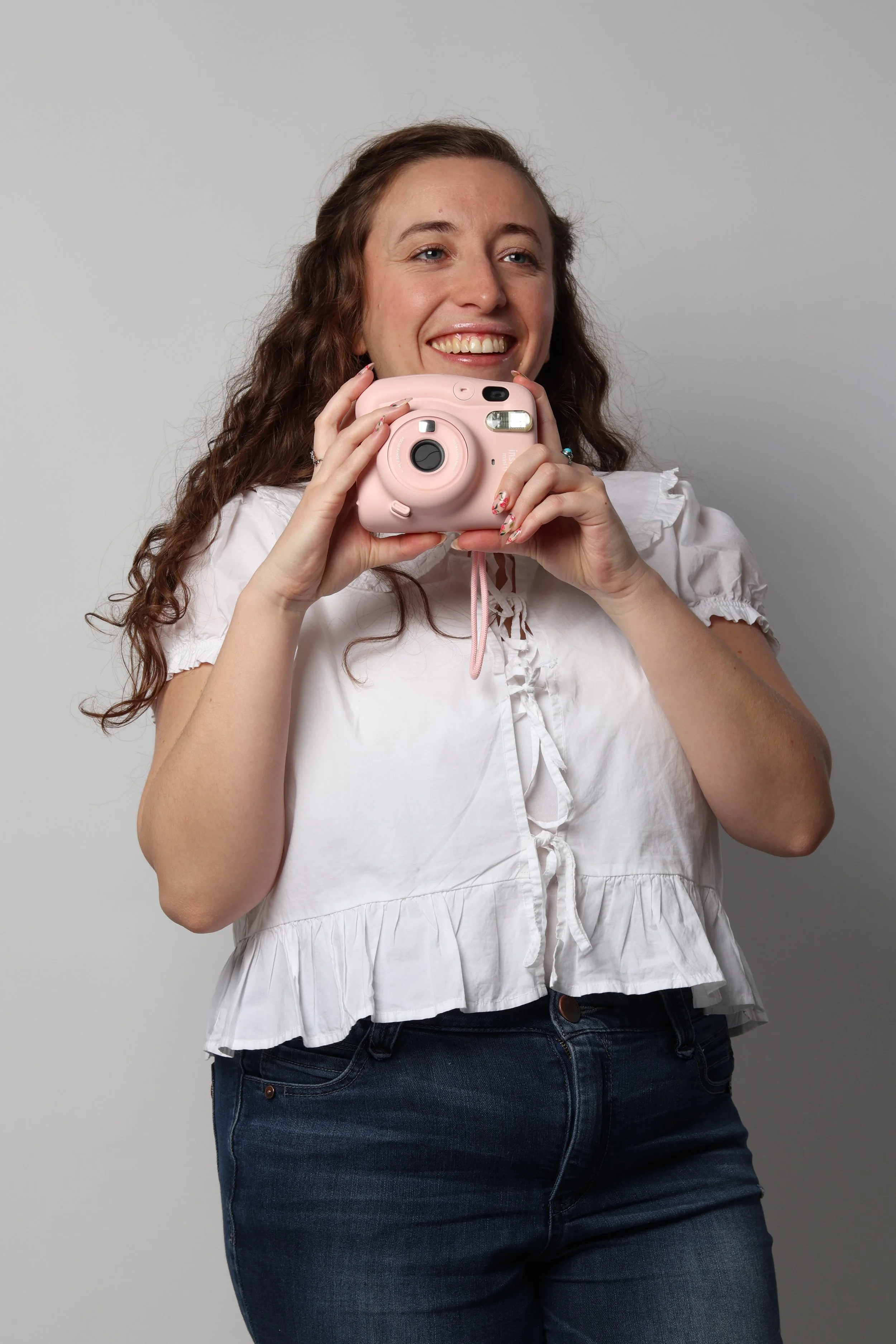 Hannah is holding a pink camera and smiling