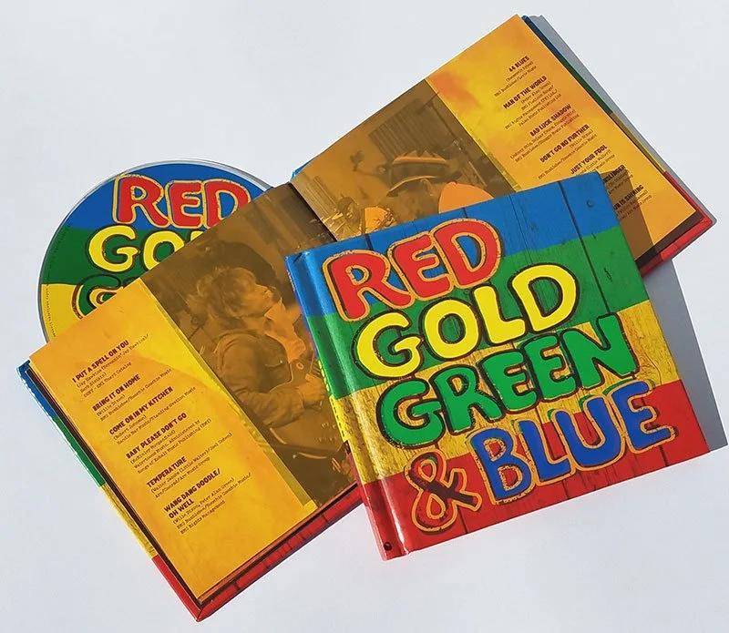 Two colorful books titled 'Red, Gold, Green & Blue' along with a CD and a booklet, on a white background.
