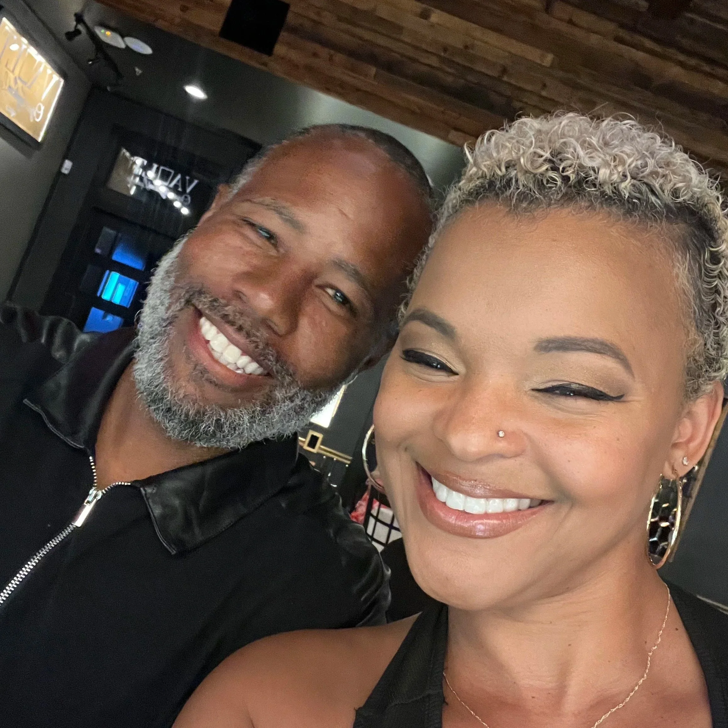 Close-up photo of a smiling man with gray hair and beard and a woman with gray curly hair, smiling.
