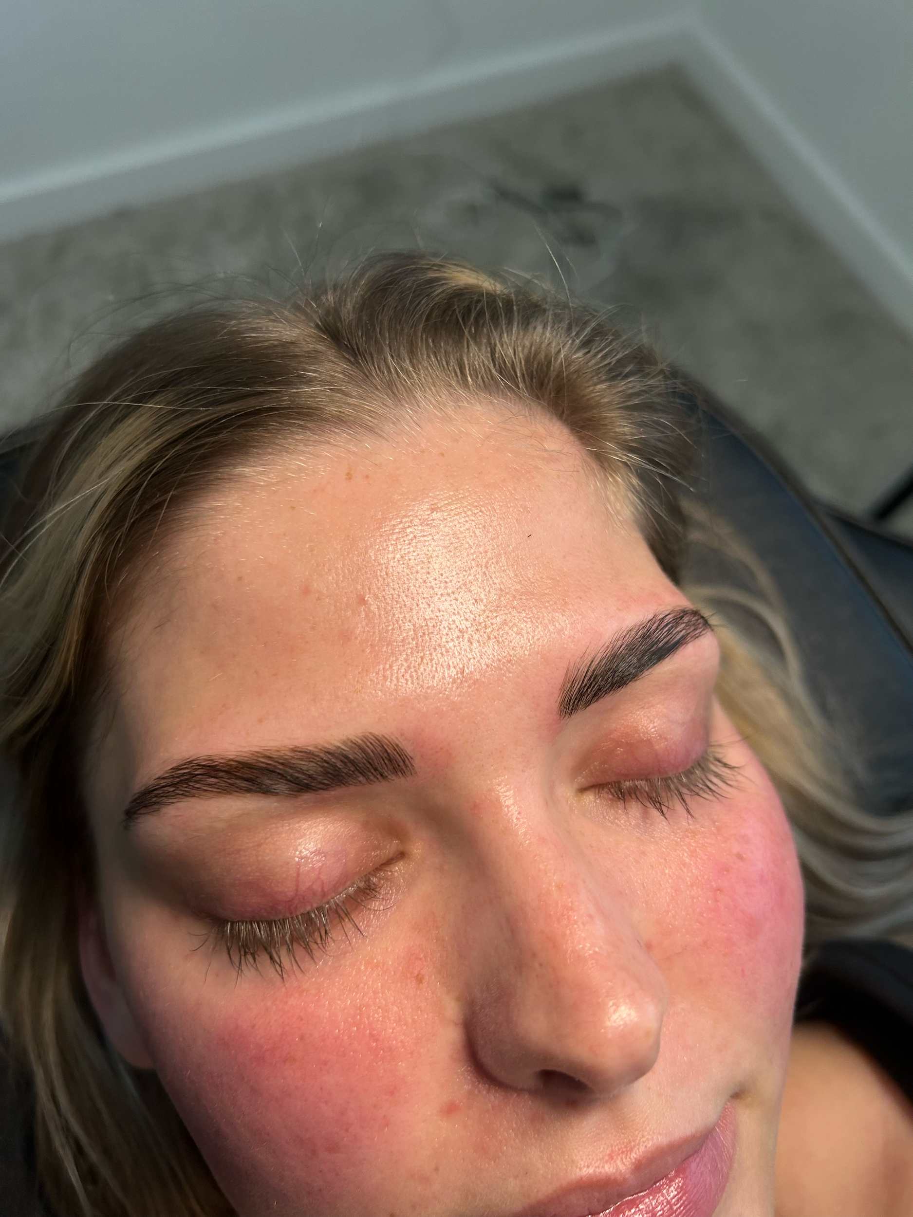 Close-up of a woman's face with freshly done eyelash extensions and well-groomed eyebrows, eyes closed.