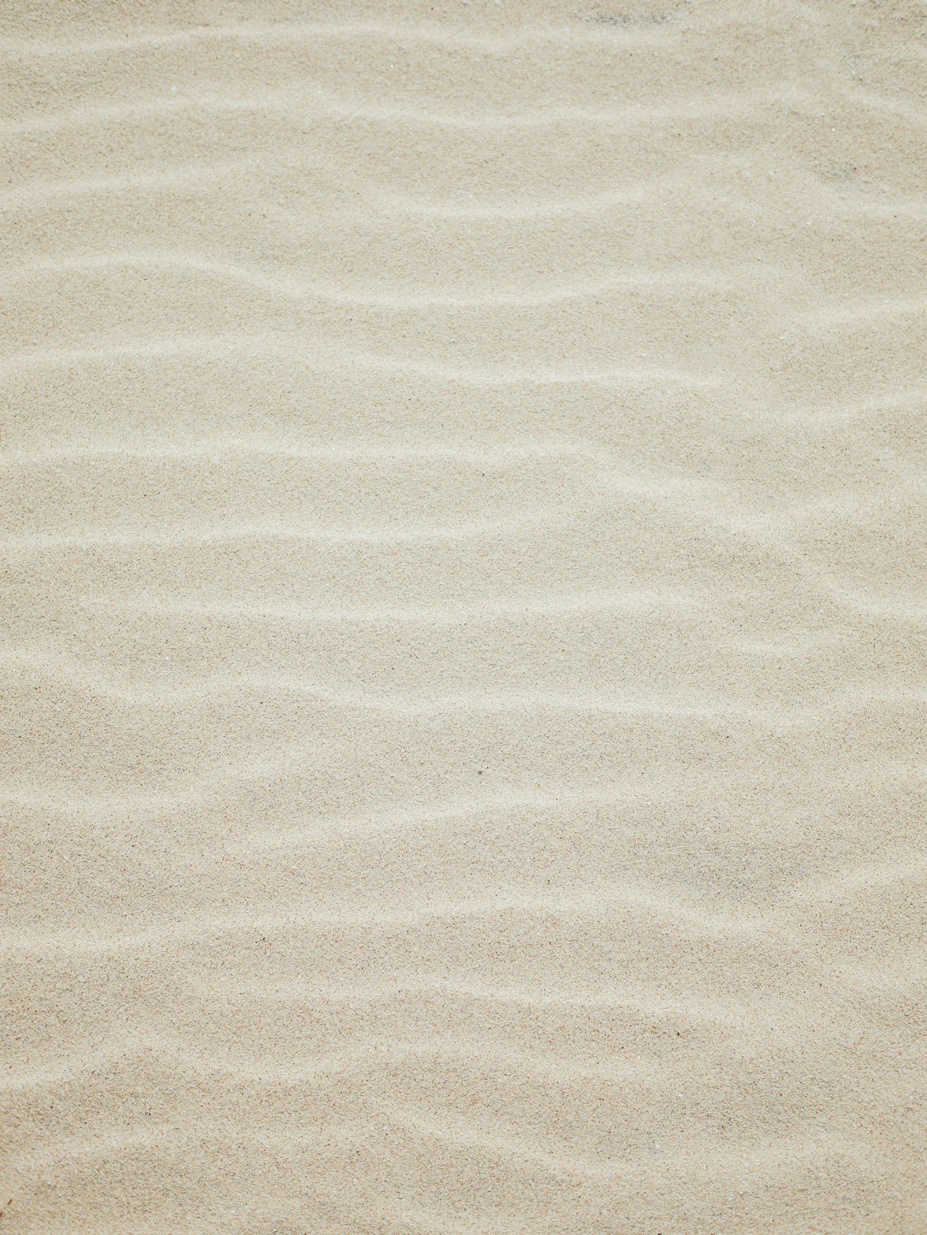Close-up of a sandy beach with small ridges in the sand.