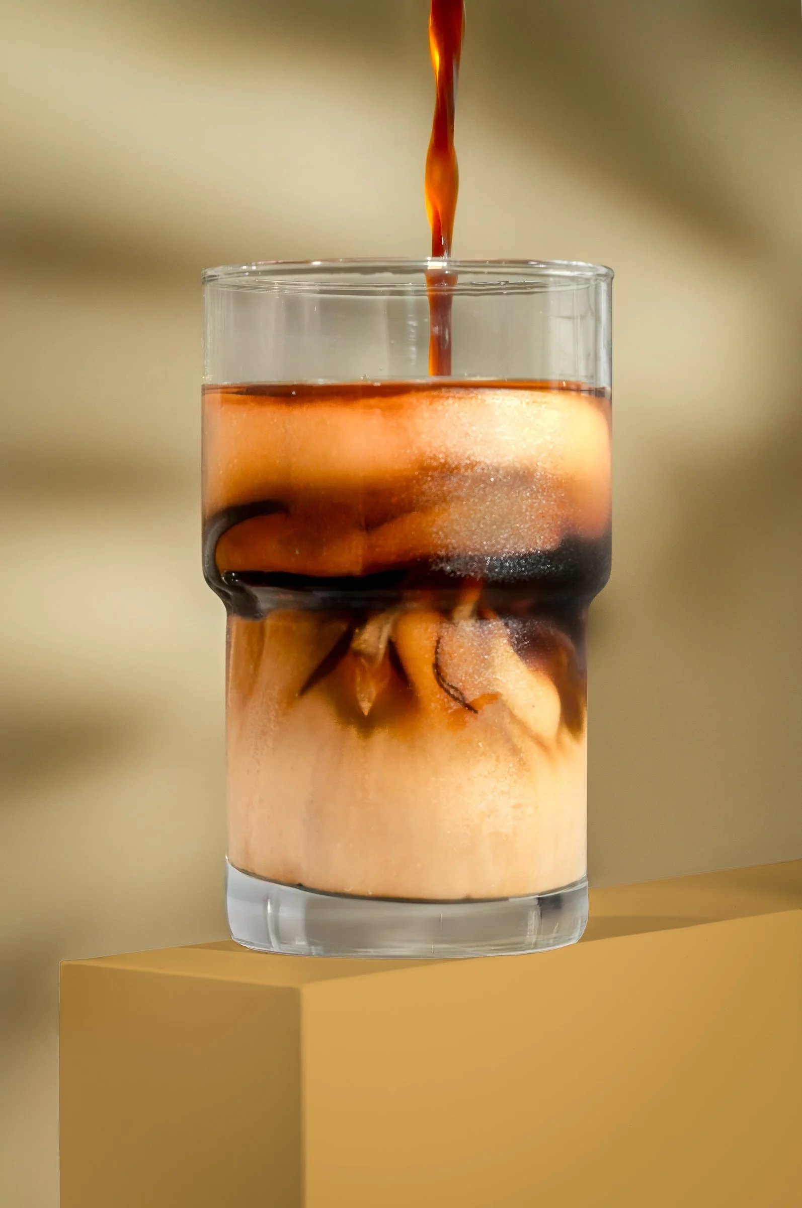 Miami beverage photographer capturing a layered iced coffee with cream and pouring espresso, styled to highlight texture, contrast, and modern drink presentation for restaurants.