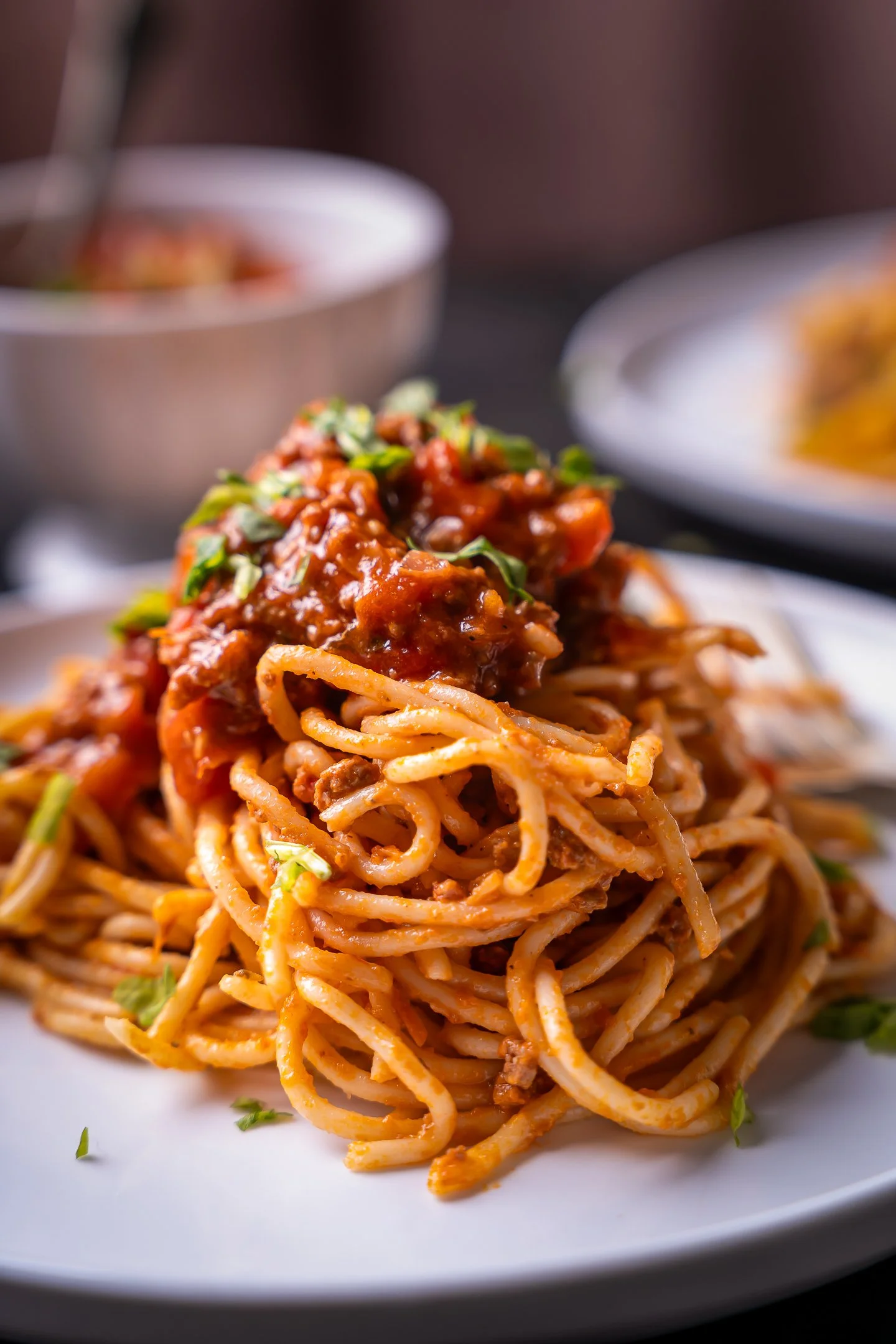 Classic Spaghetti Bolognese | Editorial Food Styling
Professional food photography of a classic Spaghetti Bolognese, featuring rich tomato meat sauce and fresh basil garnish. This high-detail shot uses shallow depth of field and warm lighting to emph
