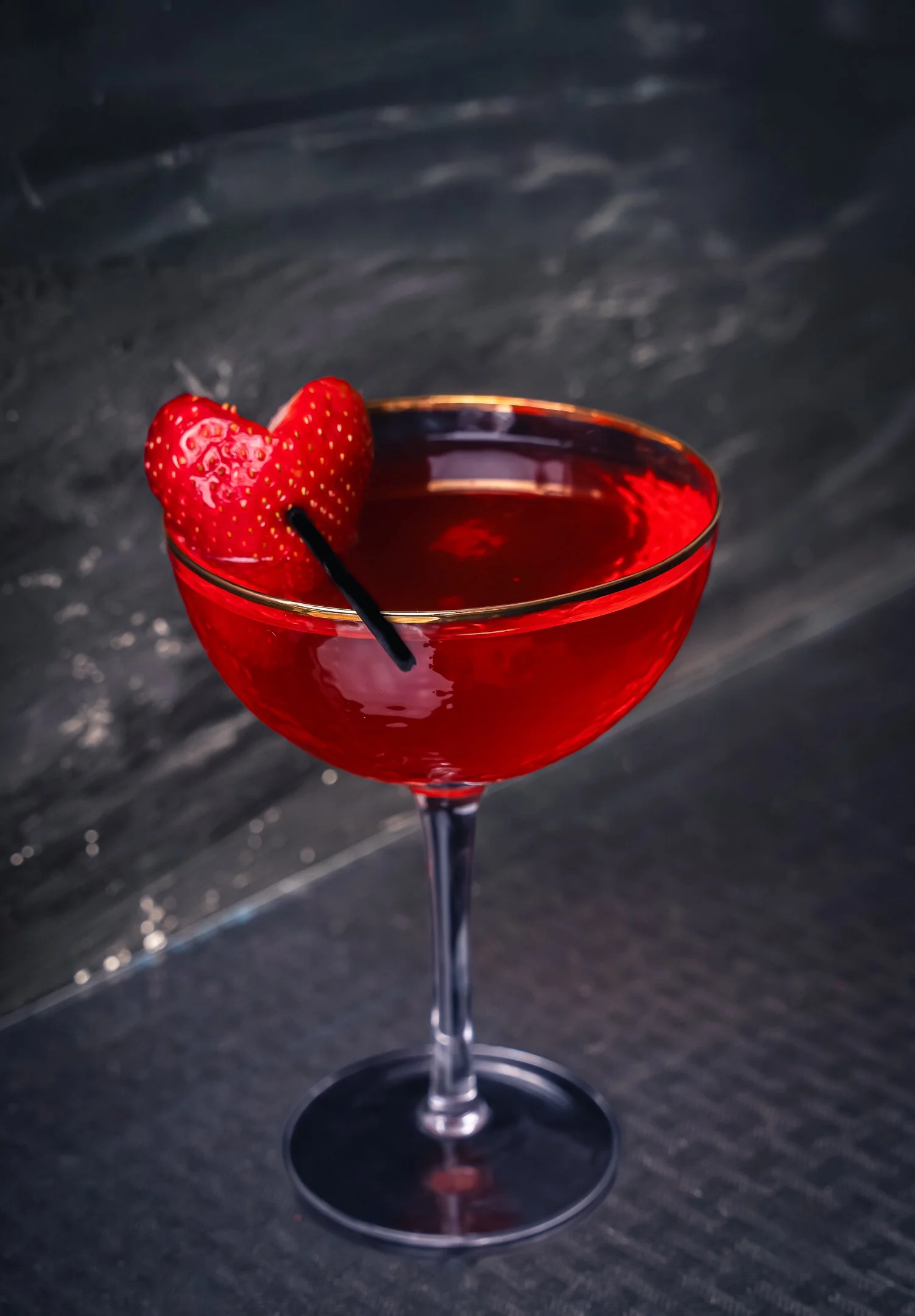 Miami cocktail photographer capturing a red cocktail with strawberry garnish in moody lighting, styled for bar, restaurant, and beverage photography.

