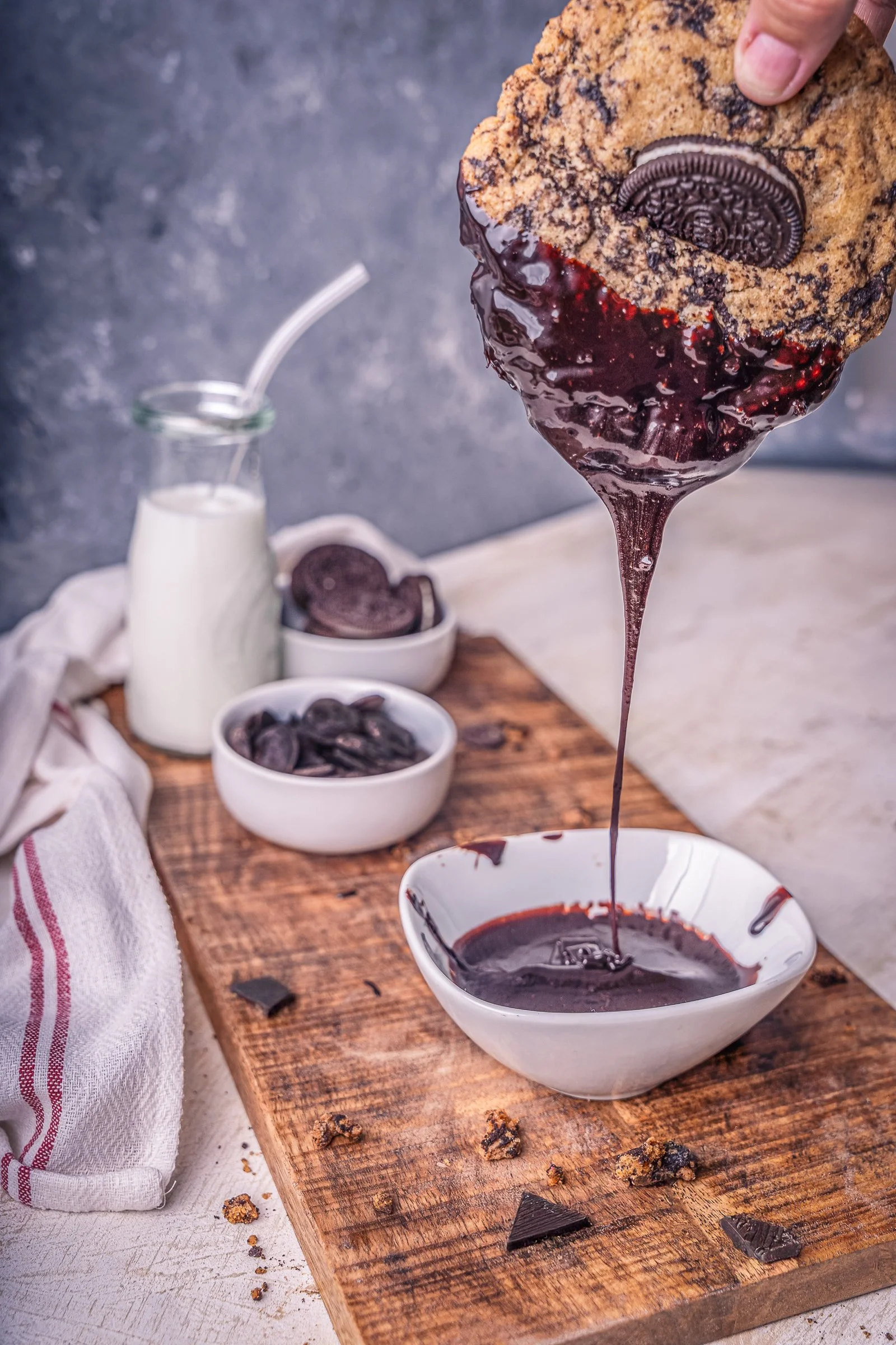 Chocolate-Dipped Oreo Cookie dessert photography
A dynamic commercial food shot featuring an Oreo-stuffed chocolate chip cookie being dipped into a rich chocolate ganache. Capturing the perfect "drip" moment alongside a bottle of milk and rustic styl