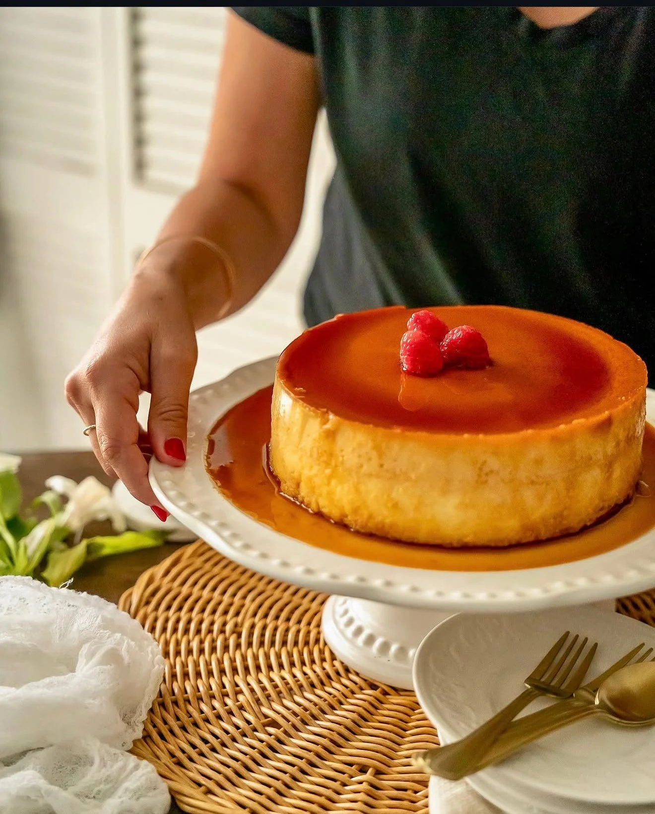 Jeannette of Jette Shoots styling a caramel flan with raspberries on a cake stand for  a dessert menu shoot.