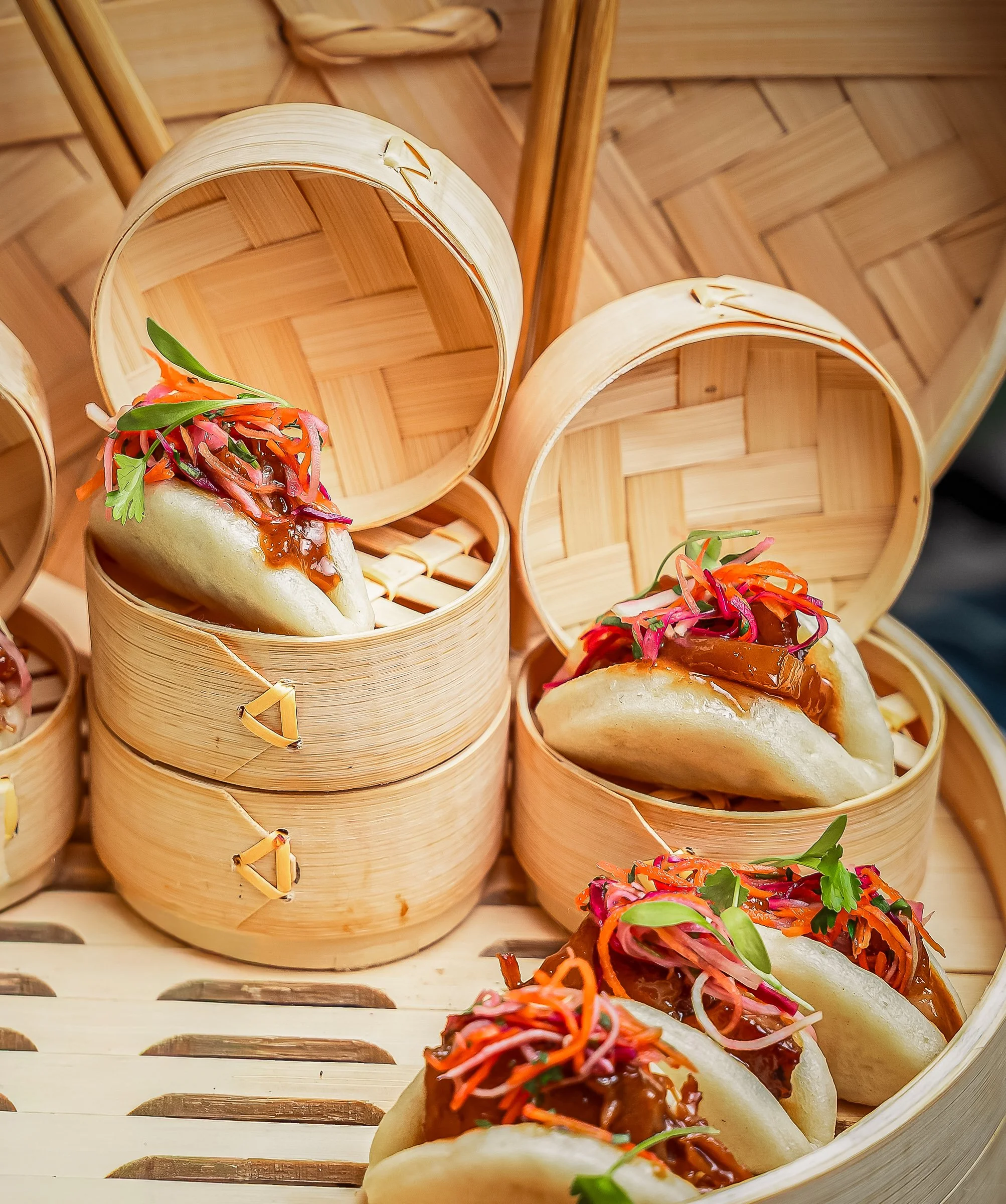 Asian Fusion Bao Bun Stylin
Professional food photography of pork belly bao buns served in traditional bamboo steamers, highlighting vibrant garnishes and textures.