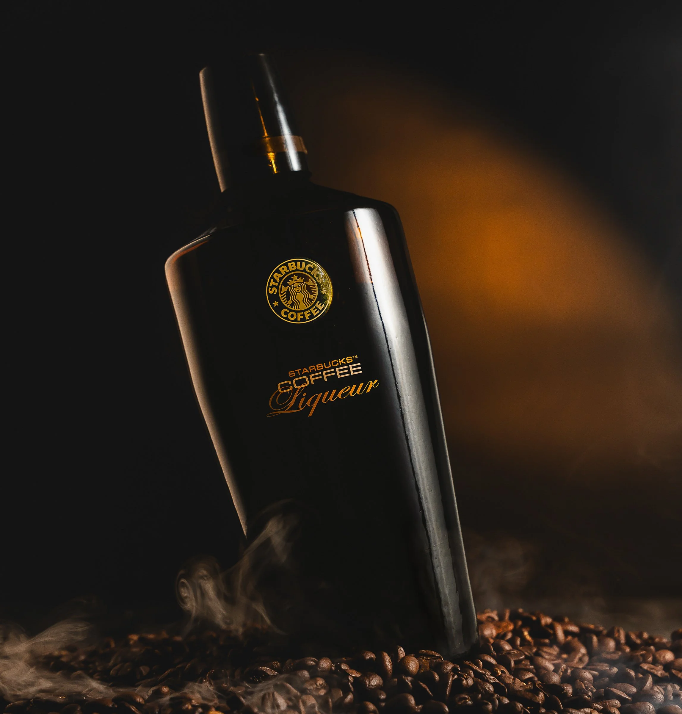 Starbucks Coffee Liqueur | Atmospheric Product
Professional product photography of Starbucks Coffee Liqueur. This dramatic commercial shot features an amber-backlit glow, swirling atmospheric smoke, and a base of roasted coffee beans. The high-contra