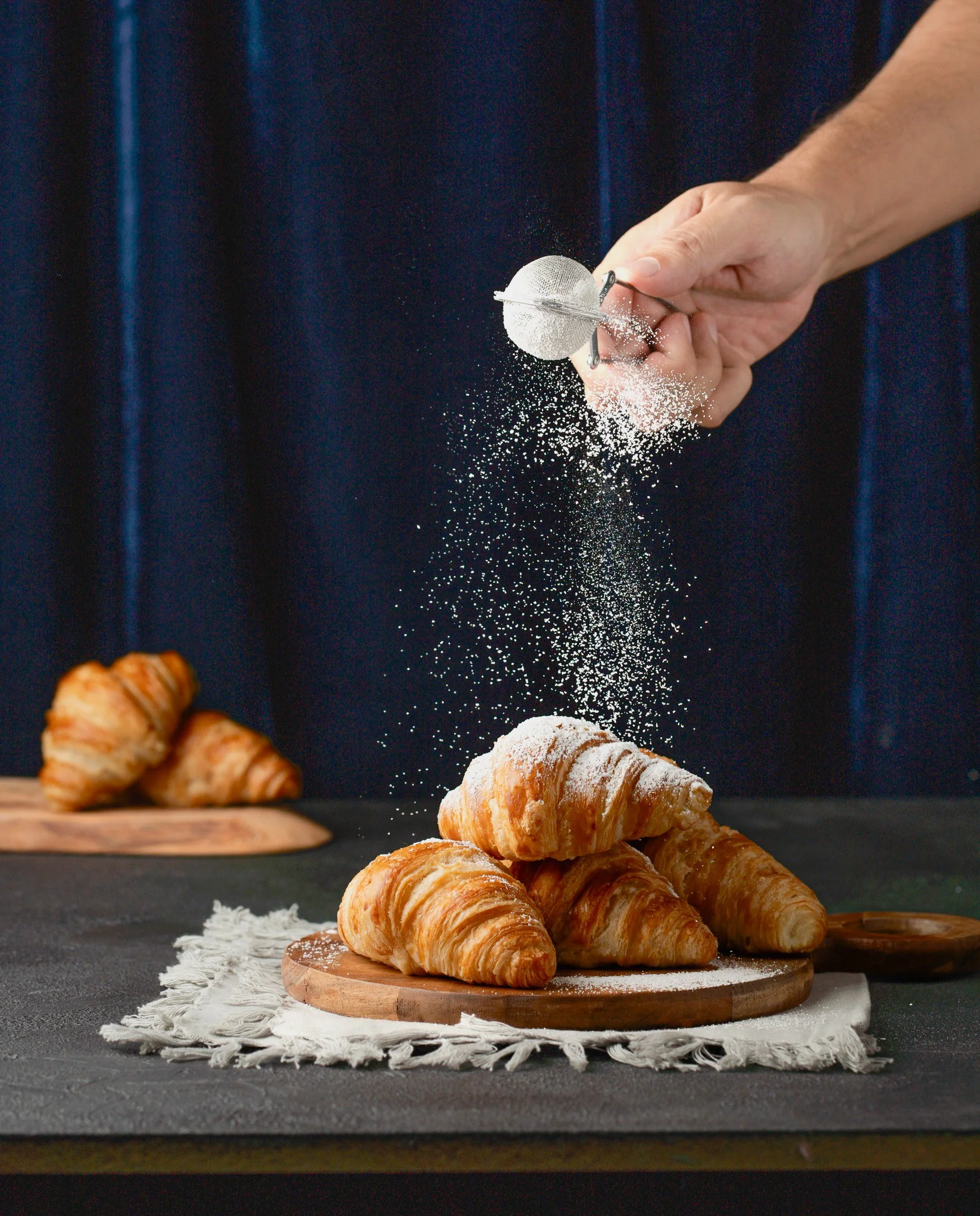 Powdered sugar dusted over croissants, food styling by Jette Shoots.