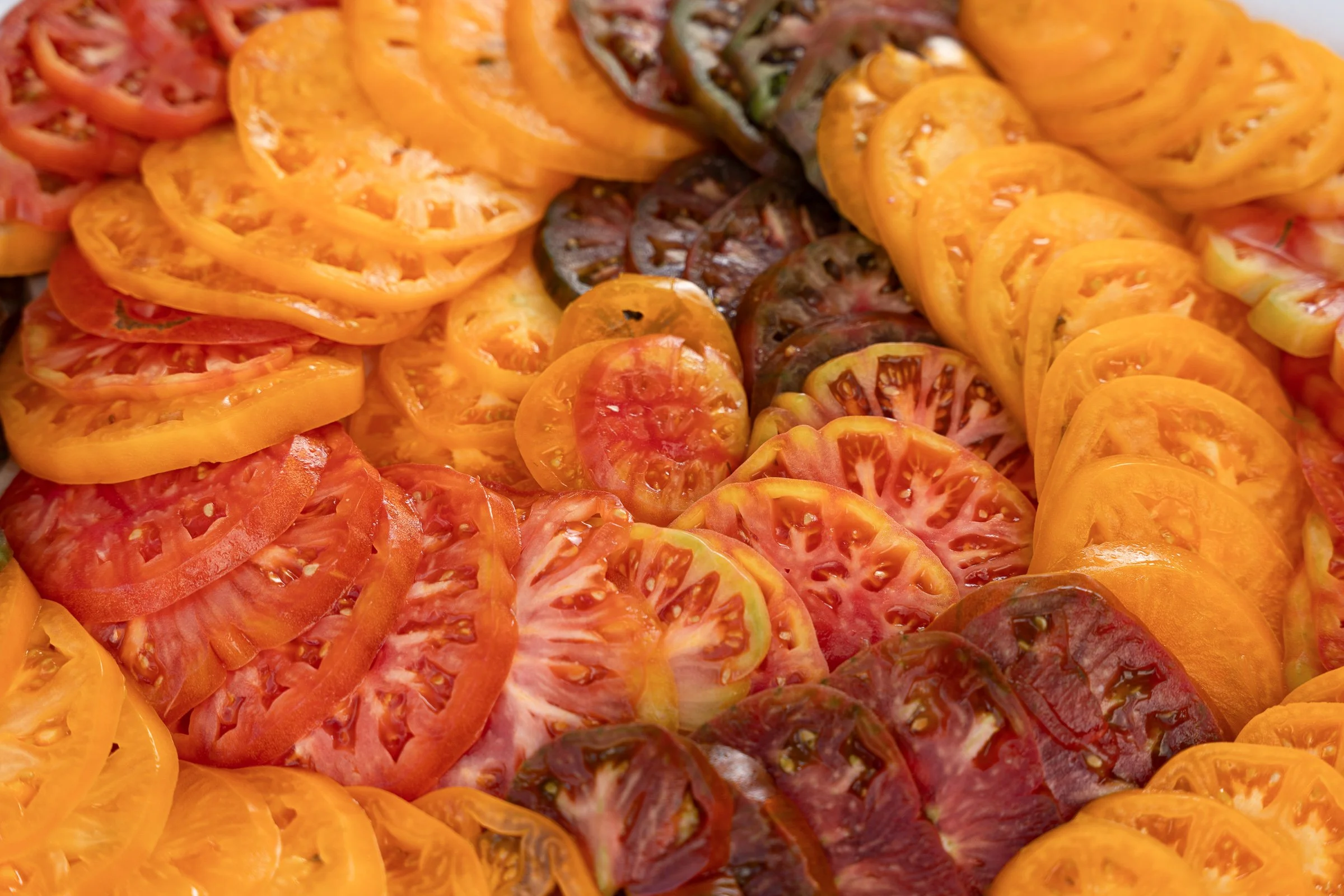 A close-up of sliced heirloom tomatoes in various colors including red, yellow, orange, and green.