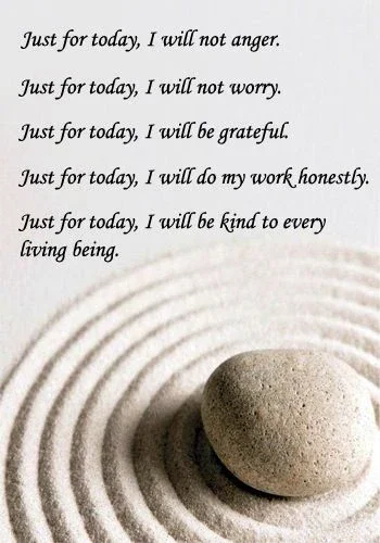 Inspirational quote about daily kindness and gratitude written on a white background with a smooth stone placed in the sand, creating ripples.