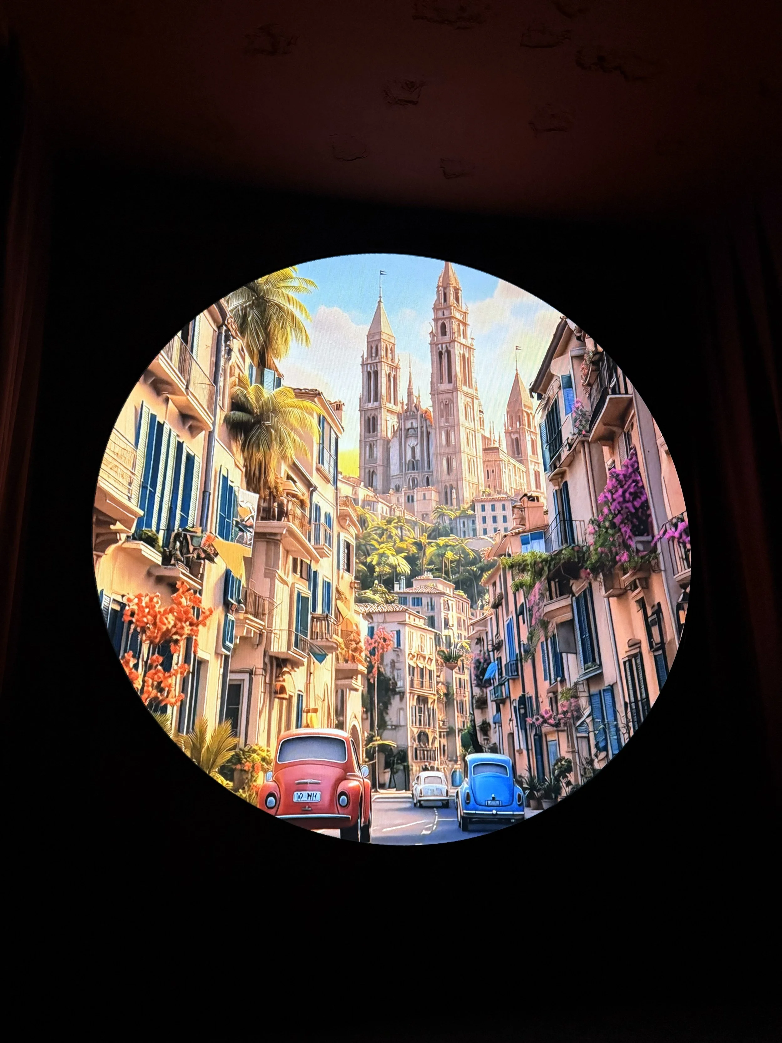 A picturesque street view of a European city with classic buildings, colorful flowers, and vintage cars, with a grand cathedral in the background.