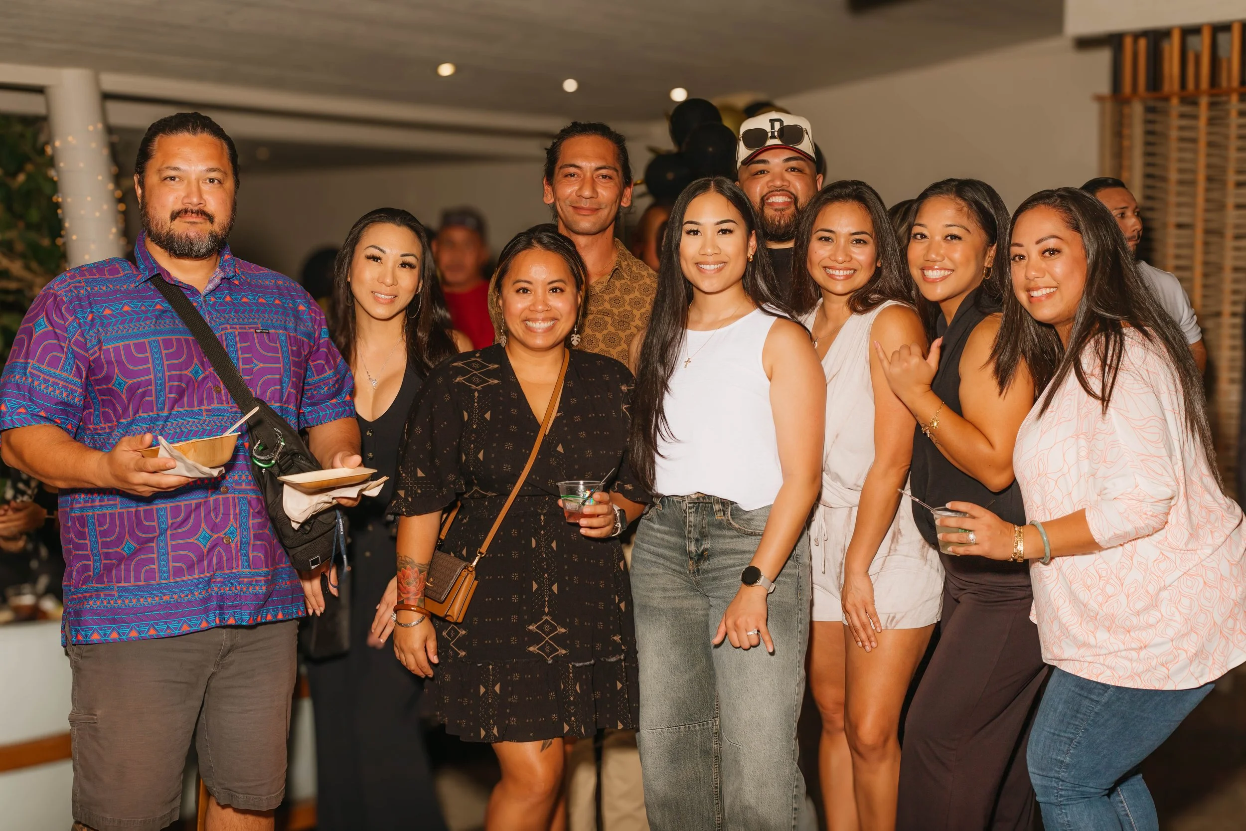 Group of ten diverse people at party, smiling and posing together indoors.