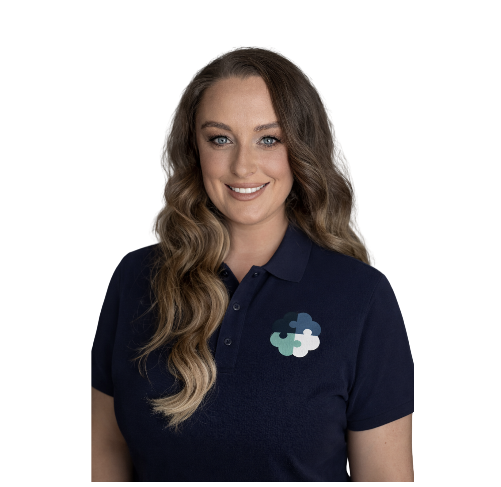 A woman with long wavy brown hair and blue eyes wearing a navy polo shirt with a puzzle piece logo.