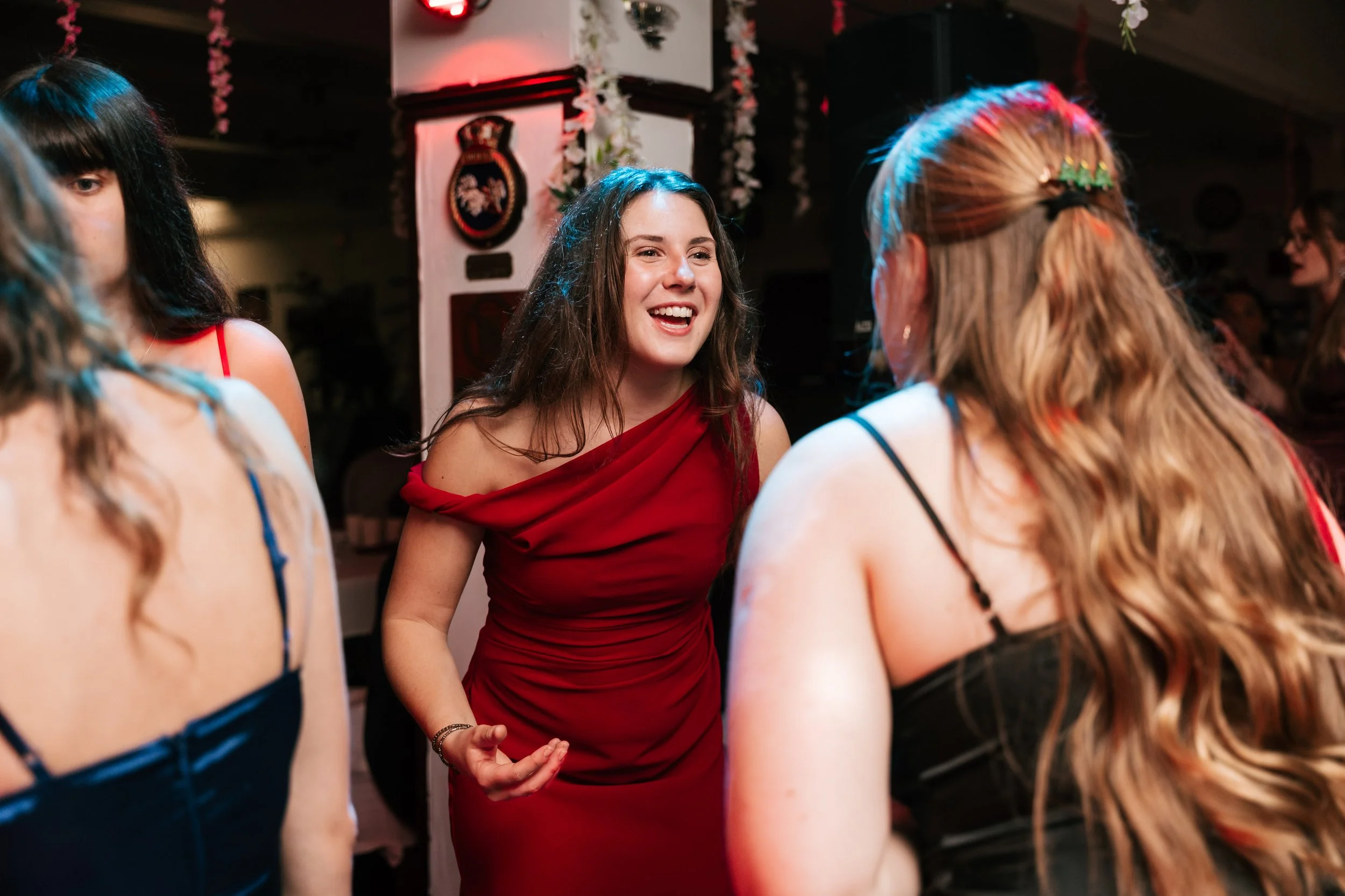 A group of women talking and laughing at a party, with Christmas decorations in the background.