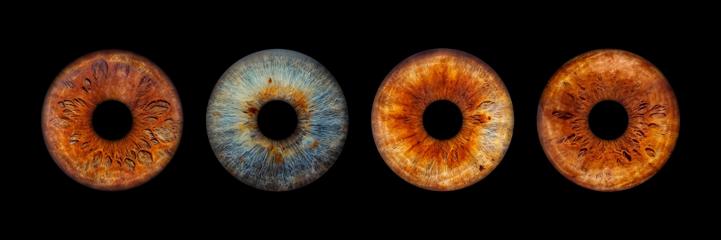 Four artificial eyes with different iris patterns and colors against a black background.