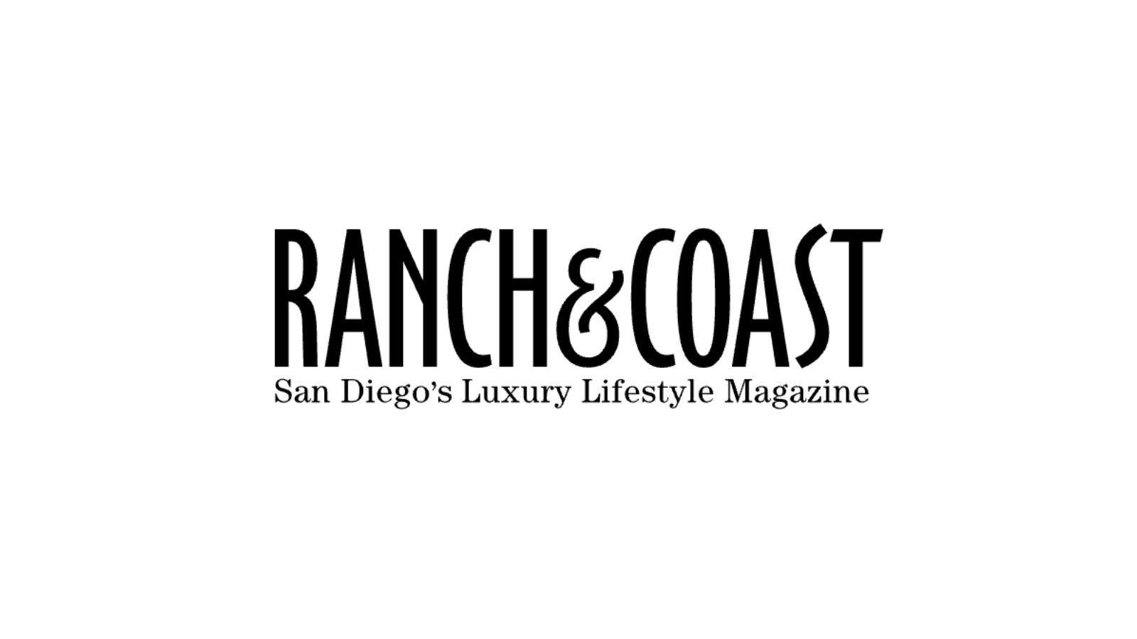 A man with gray hair wearing a blue sweater and beige pants sits on a neutral-colored bench, looking to his right with a calm expression. Shadows cast on the beige wall behind him.