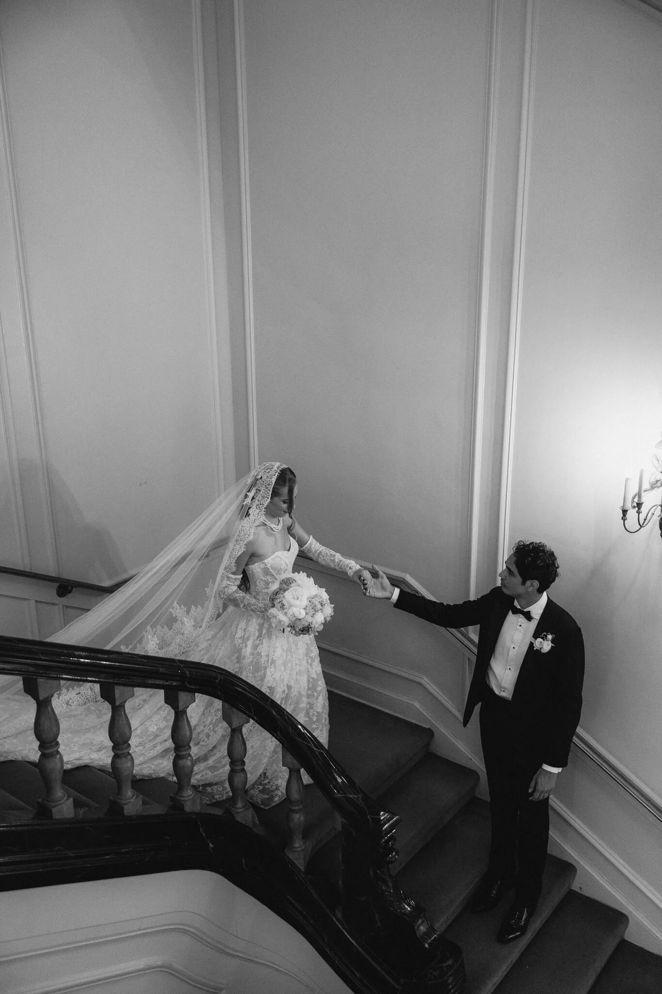 Groom leading  bride on mansion staircase