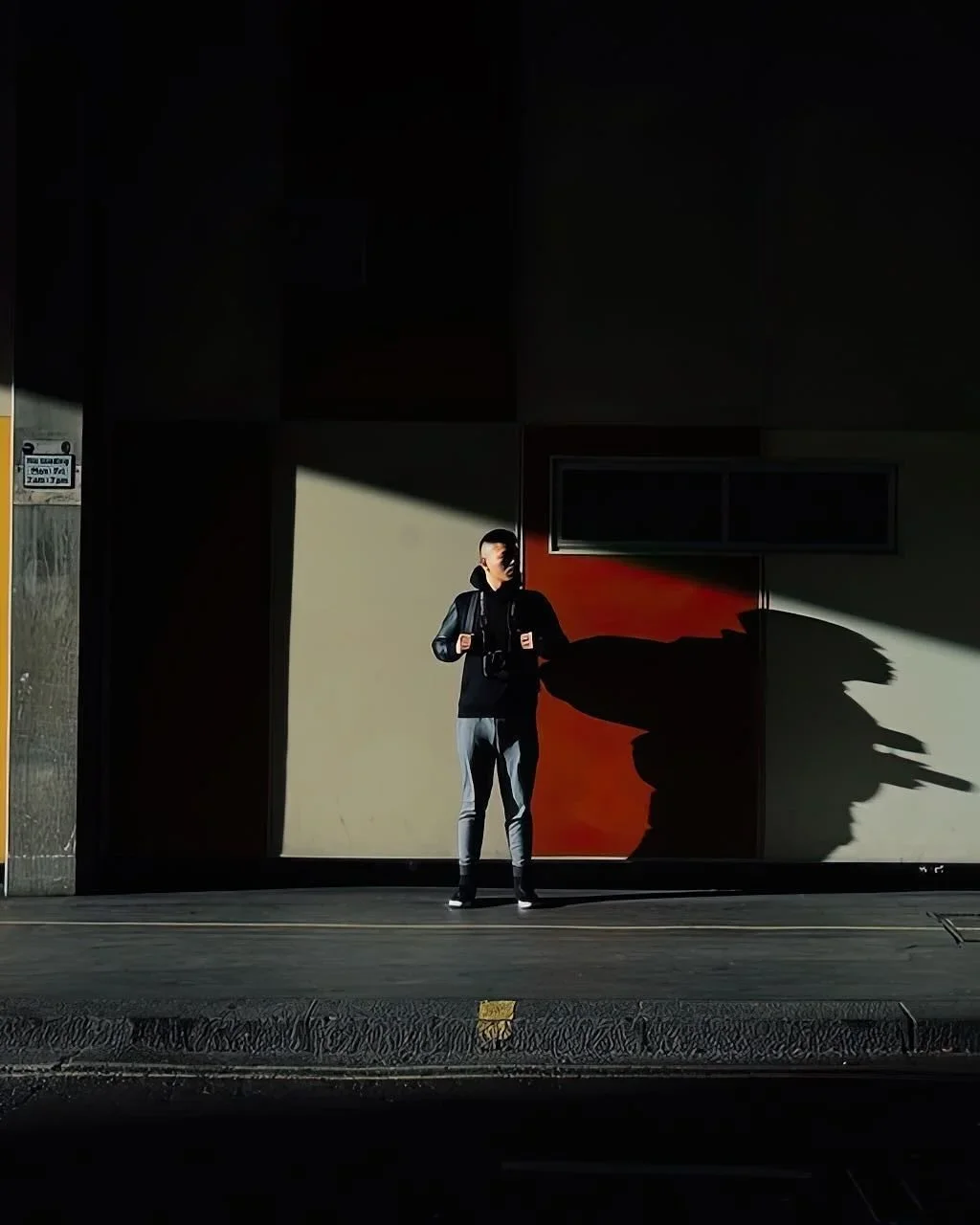 Person standing in dramatic shadow and light against colorful urban wall