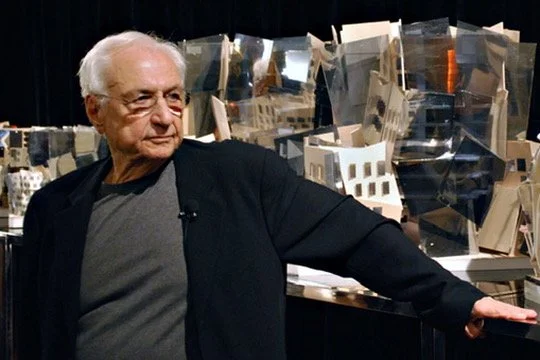 Frank Gehry at the UTS Business School launmch standing in front of display models of buildings.