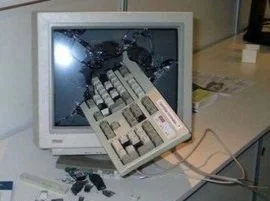 Photo of broken vintage computer monitor with vintage keyboard jutting from the screen