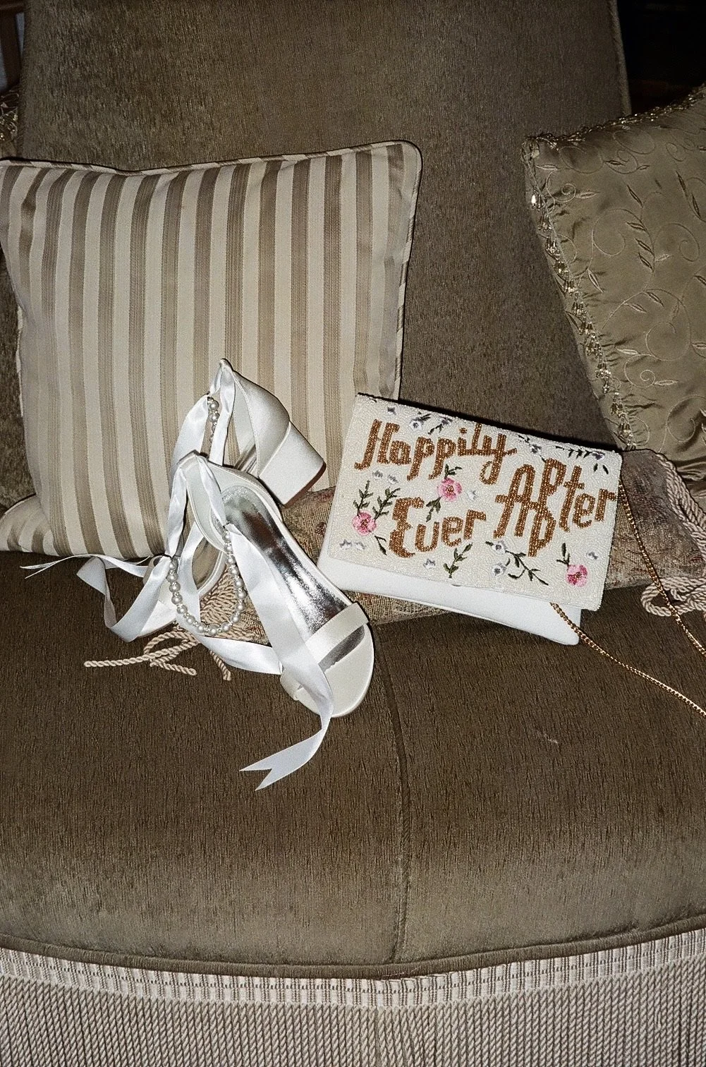 Bridal getting-ready flat lay with white high heels, a pearl bracelet, and a floral embroidered clutch, the kind of romantic detail styling that inspires IL Weddings & Events' Central Virginia brides.