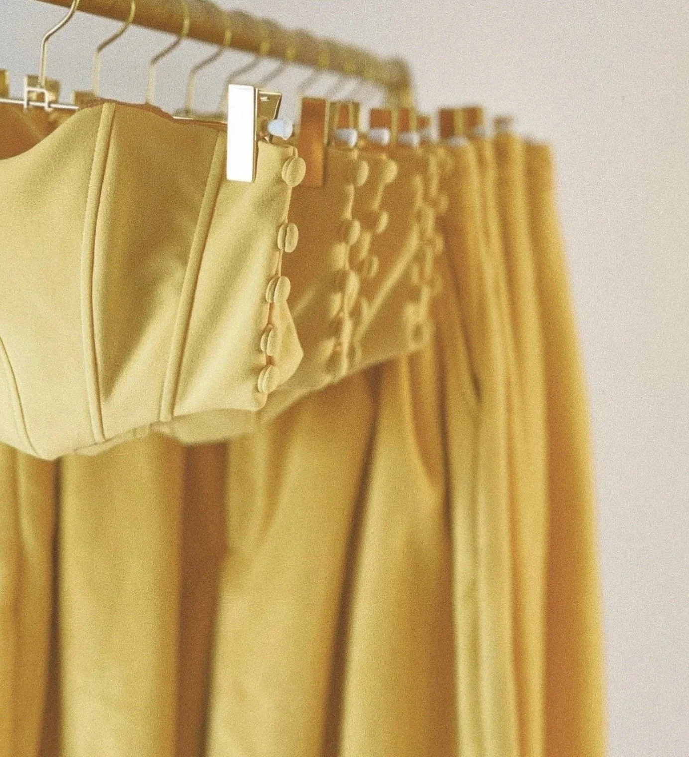 Yellow fabric curtains hanging on a metal rod with clips.