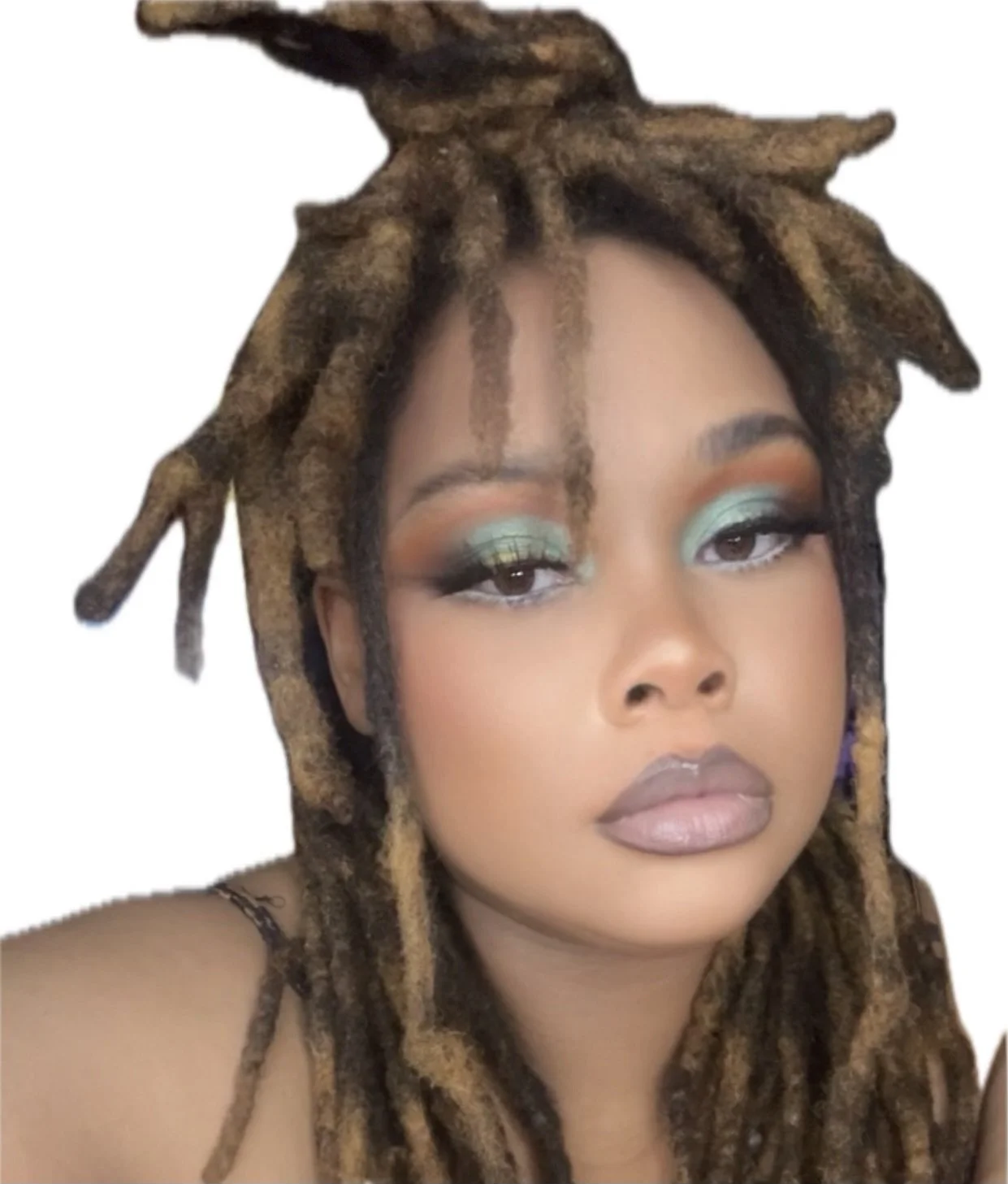 Close-up portrait of a woman with dreadlocks and makeup, looking at the camera.