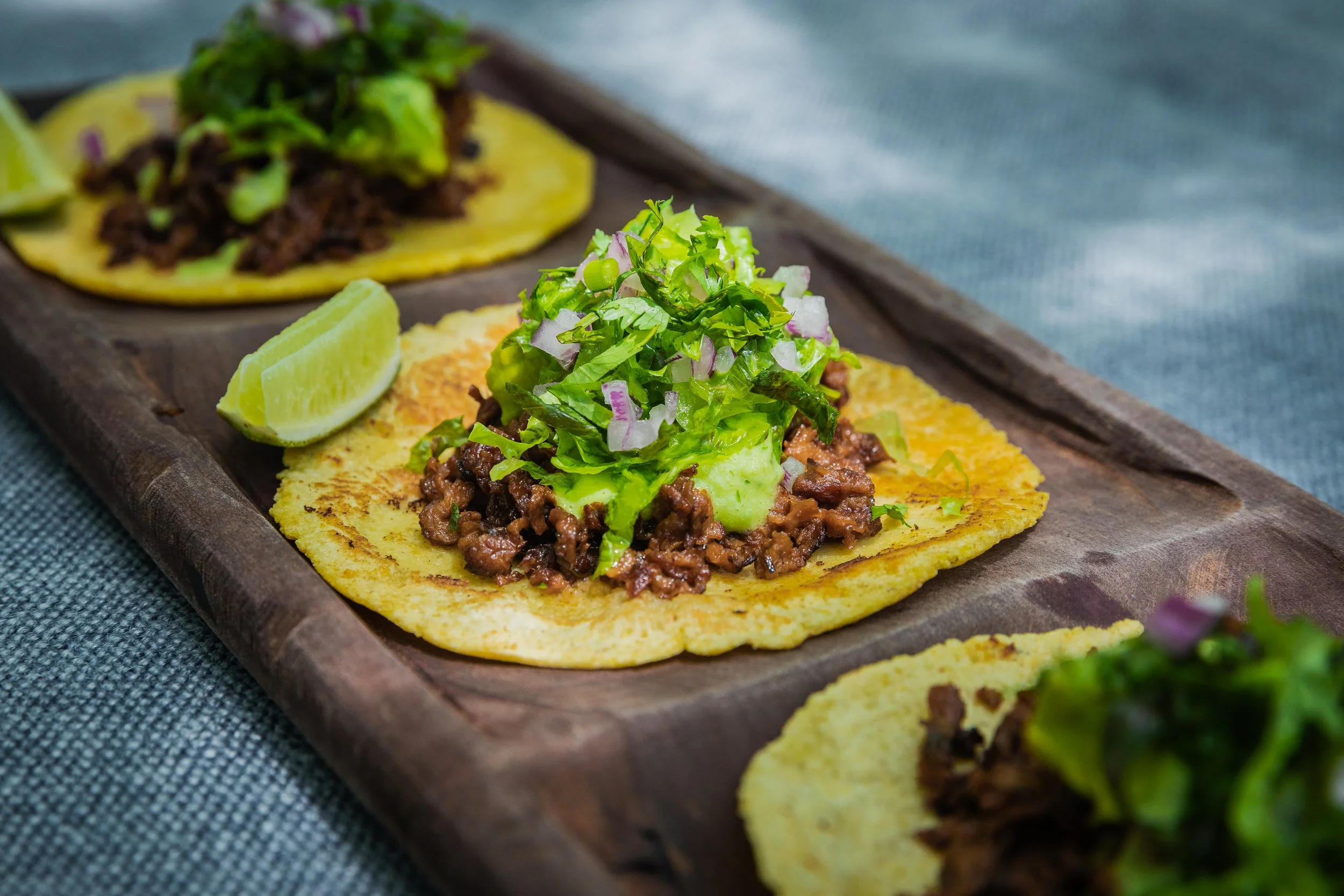 Close-up of two street-style tacos on a wooden serving tray. Fuel up during a Mahjong Retreat!