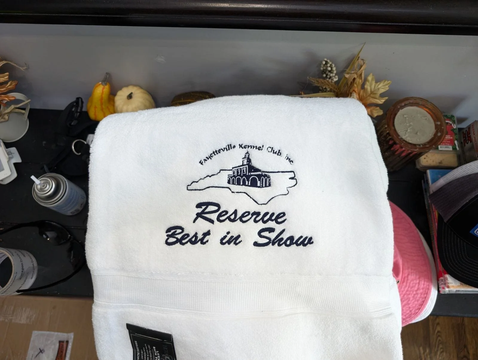A white towel with an embroidered logo and text for Fayetteville Kennel Club Inc, featuring a building and the words 'Reserve Best in Show'.