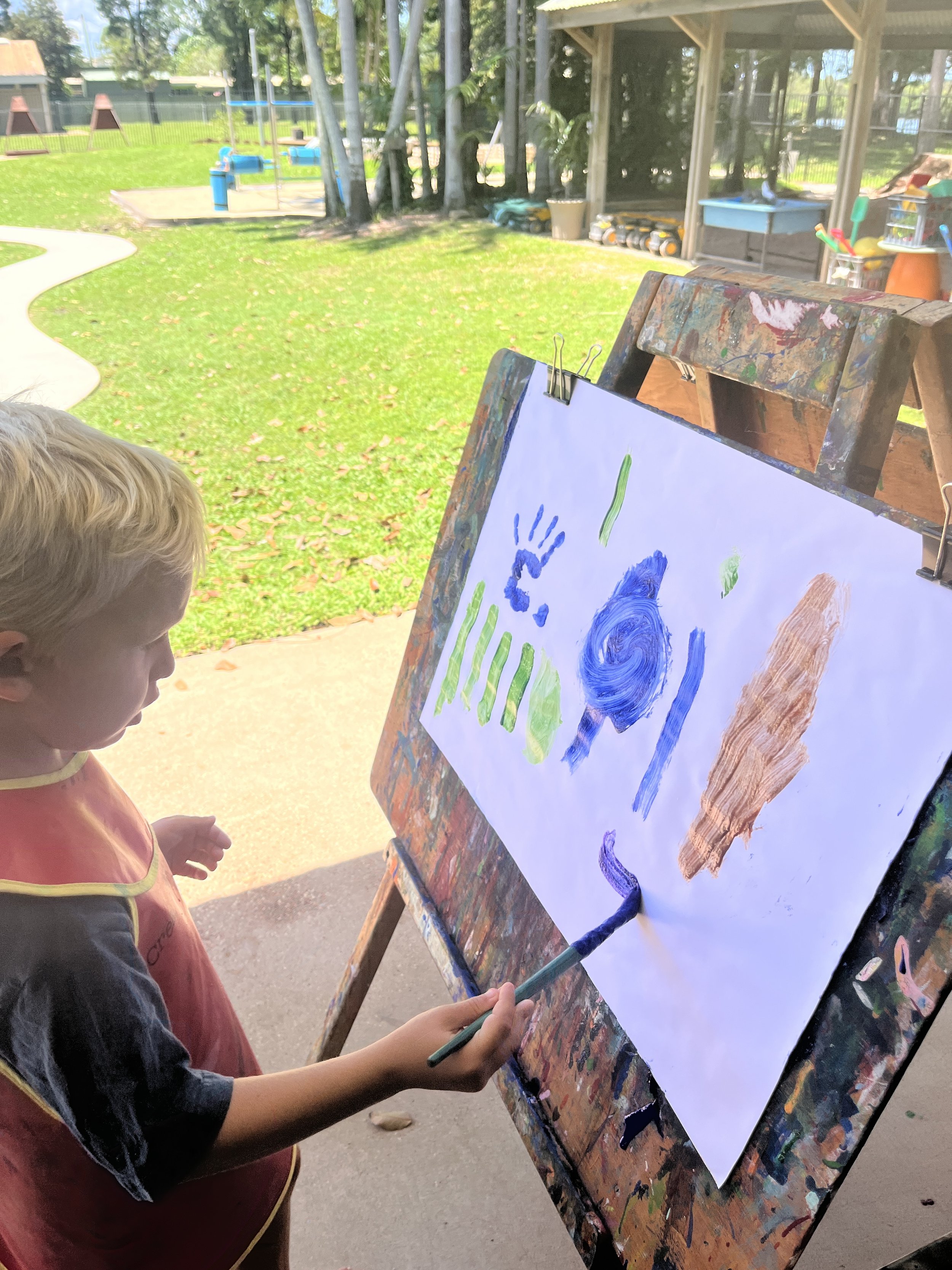 Child painting overlooking playground