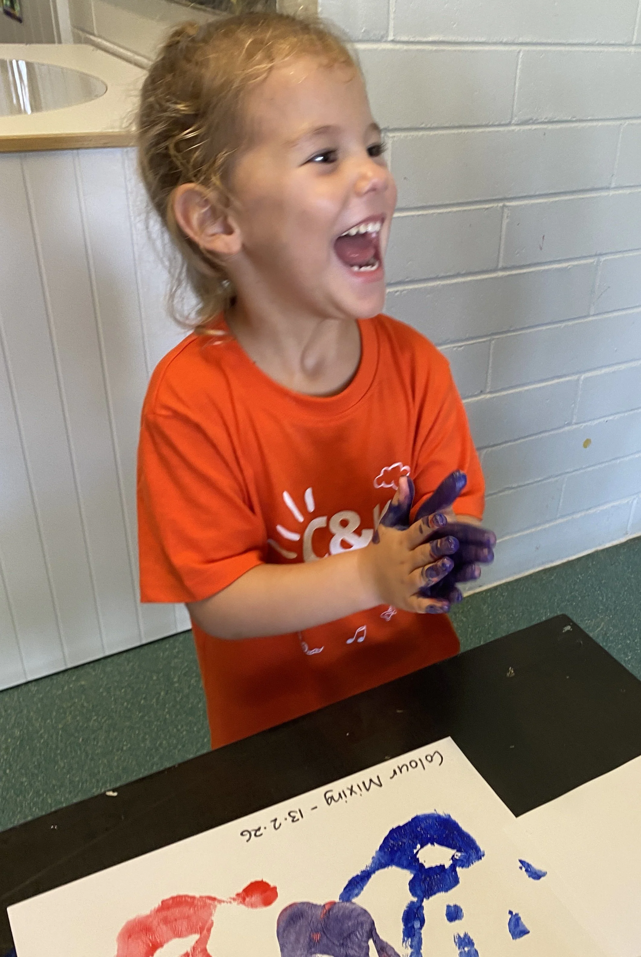 child laughing with painted hands
