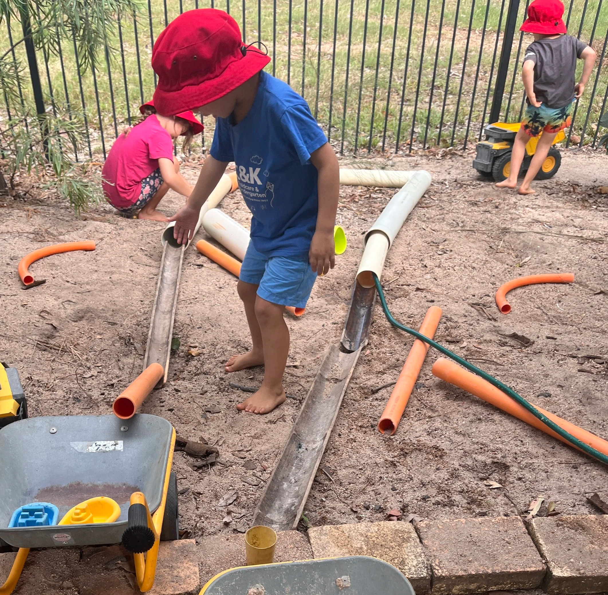 child in sandpit making water tunnel