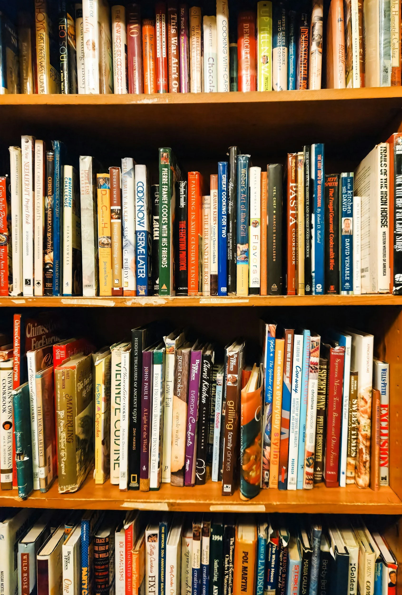 Bookshelves filled with various hardcover and paperback books in a library or bookstore.