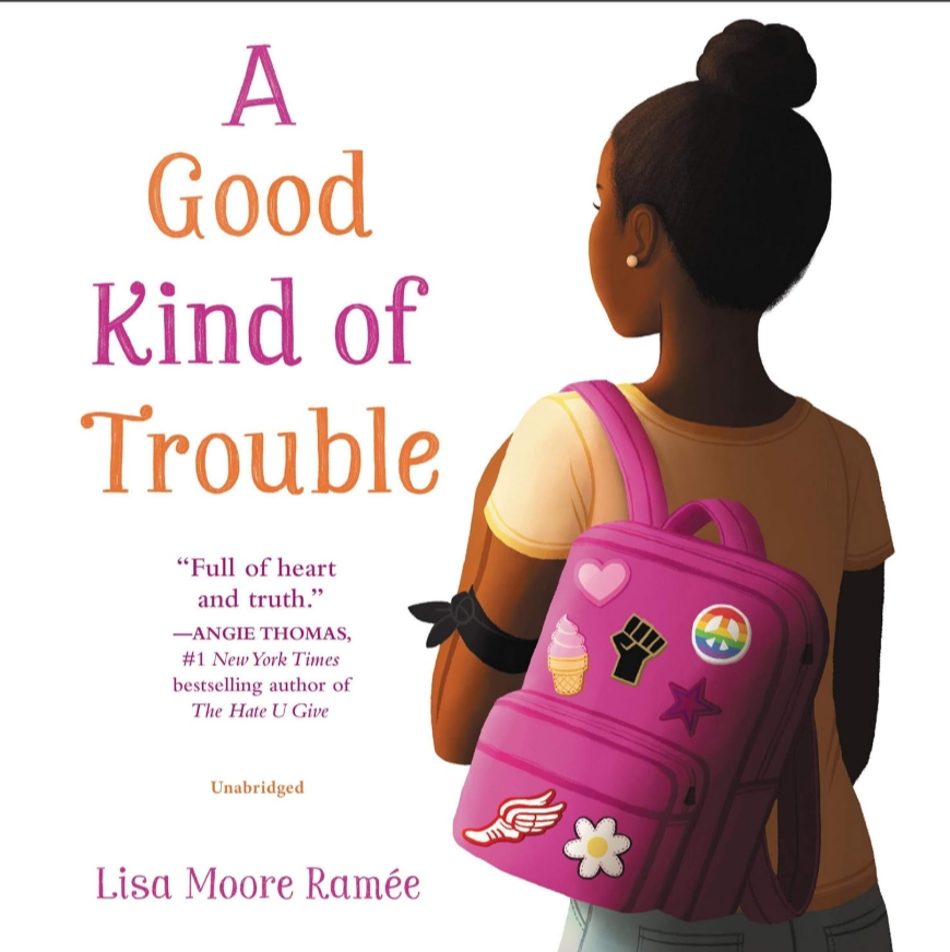 A girl with dark skin and black hair in a bun, wearing a beige T-shirt with cut-out shoulders, holding a pink backpack decorated with various patches, and looking to the right. The book title is "A Good Kind of Trouble" with author Lisa Moore Ramée, featuring a quote from Angie Thomas.