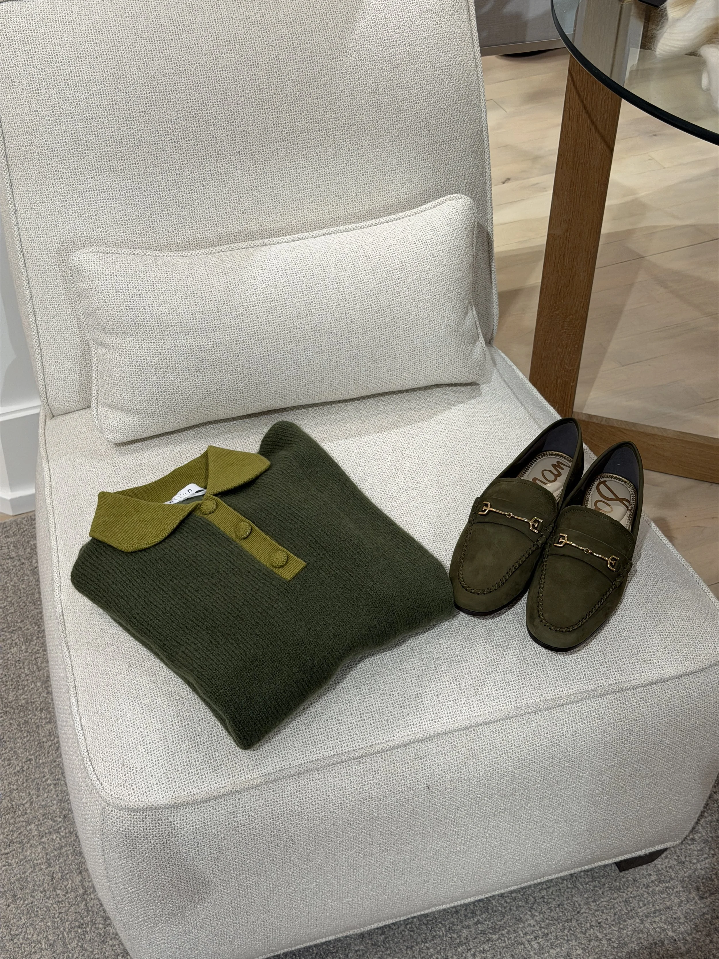 A green suede sam edelman loafer and a collared green sweater shirt laying on a white chair