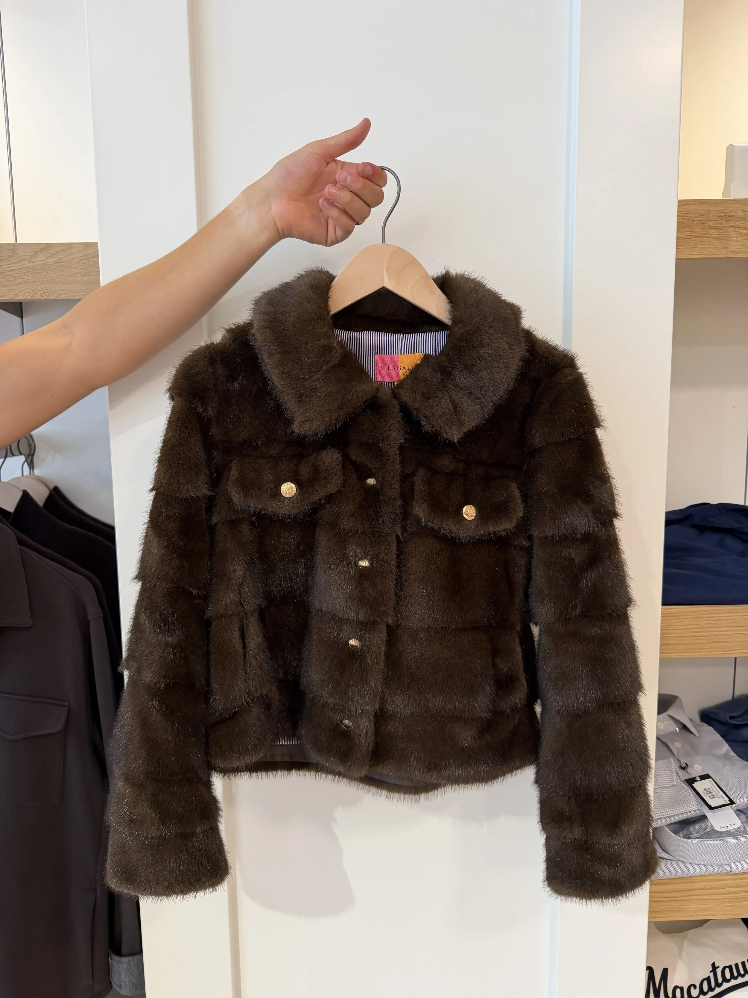 A man holding a brown fur coat with gold buttons