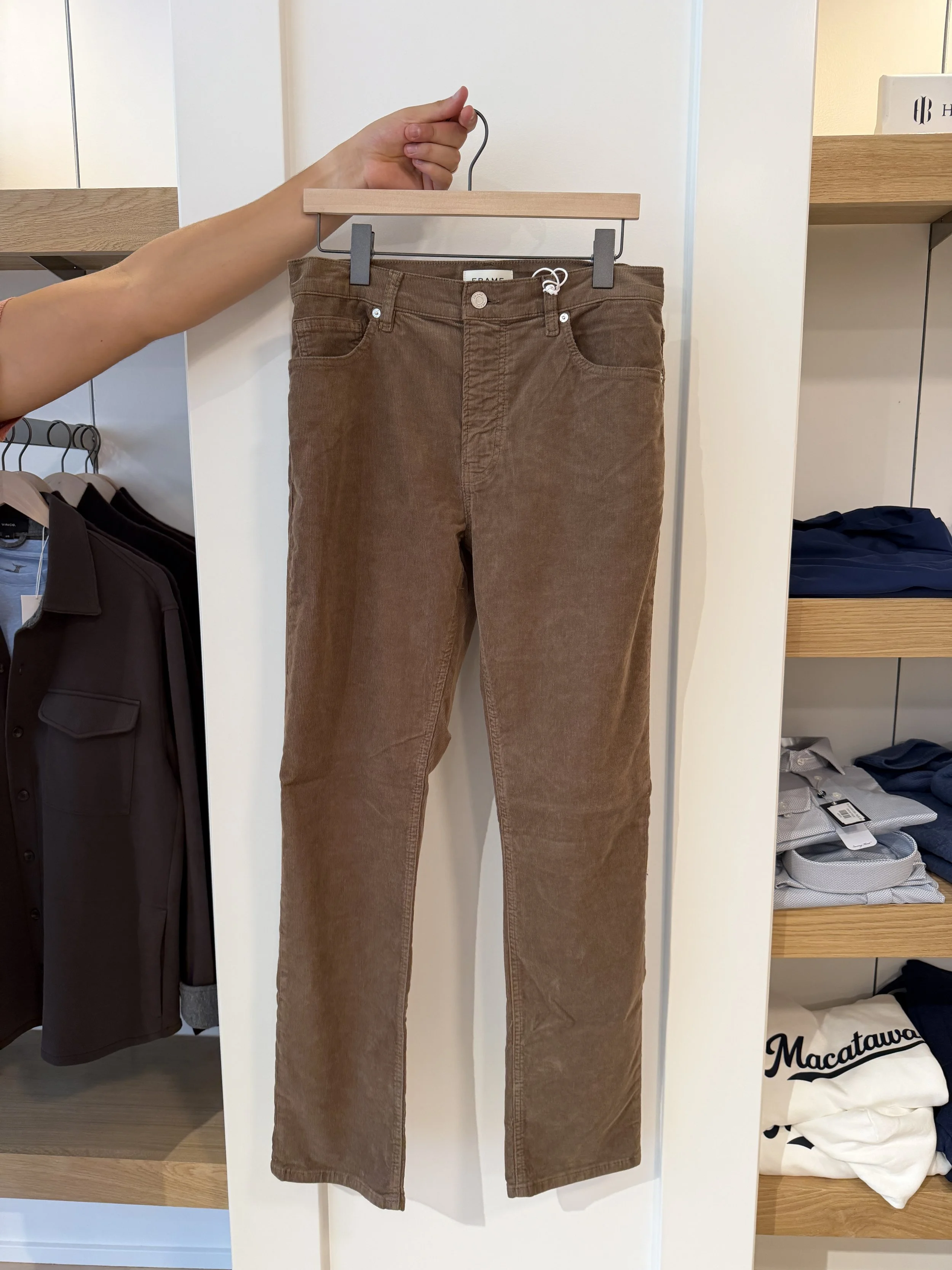 A man holding up a pair of brown corduroy pants