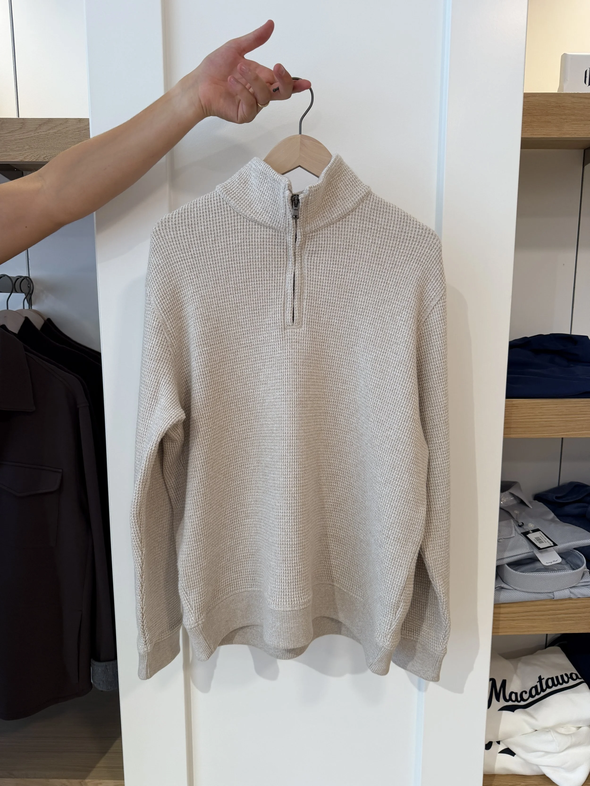 A man holding a cream long sleeve half zip vince sweater