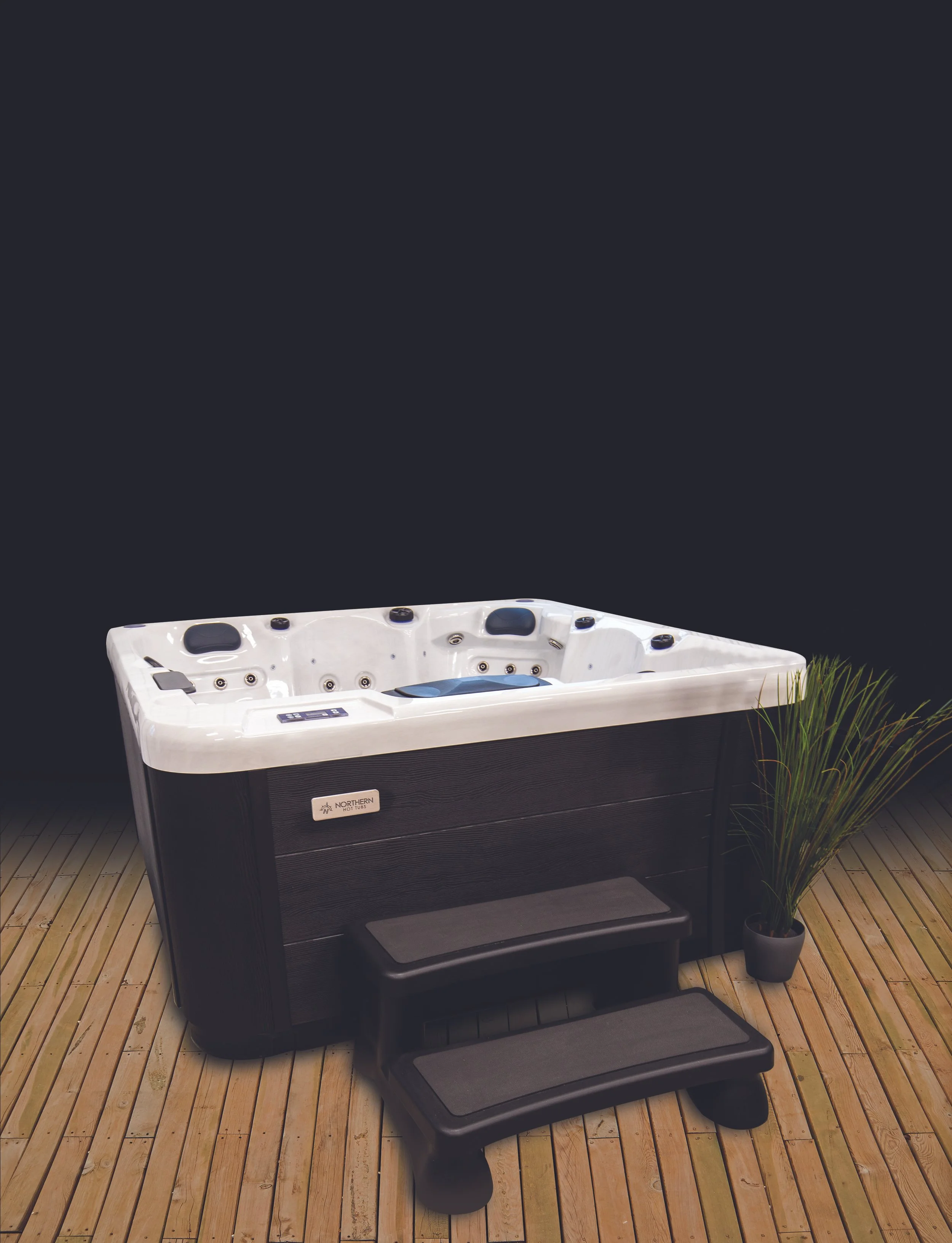 A Northern Leisure hot tub with steps on a cedar deck at night