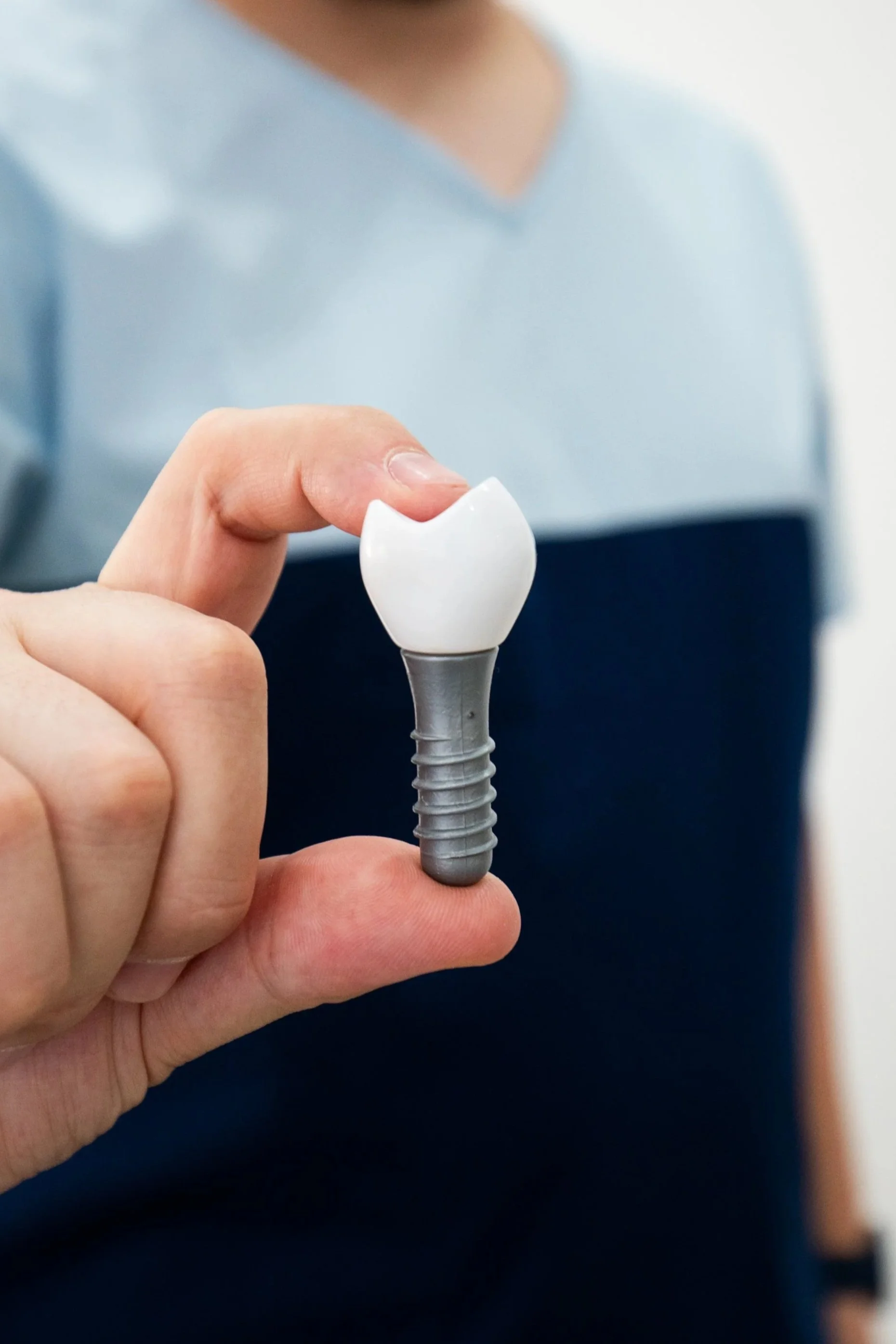 Mano sosteniendo una réplica de un implante de diente dental