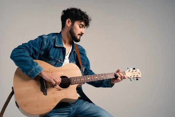 Man playing an acoustic guitar in a studio setting