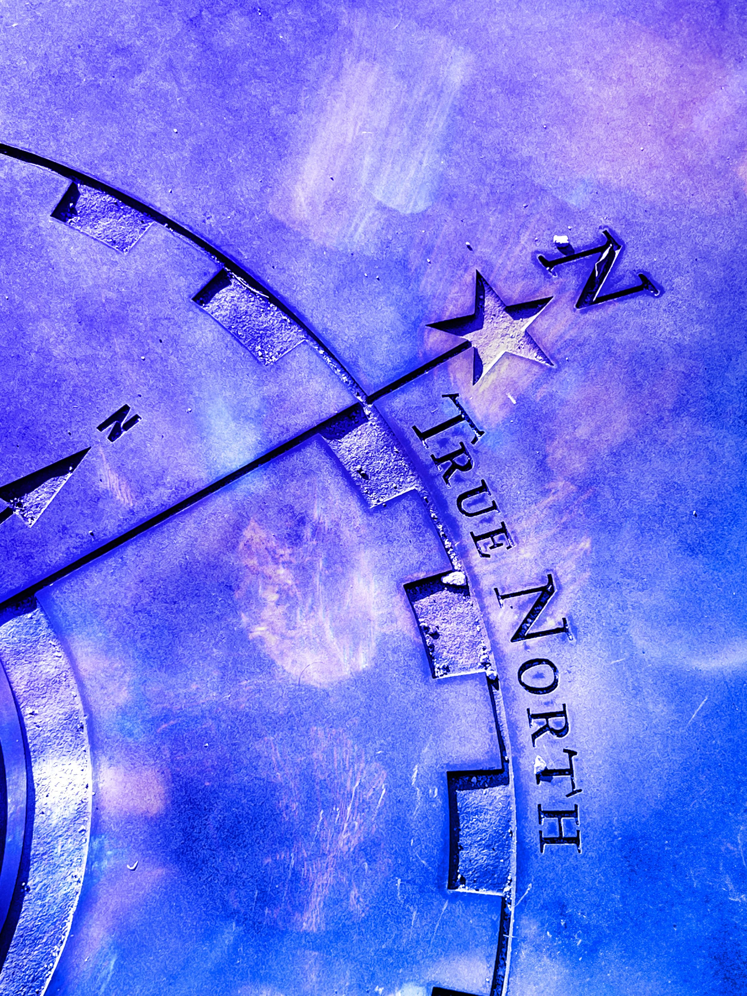 Close-up of metal lettering spelling 'TRUST' and a star shape cut-out on a textured surface with hues of purple and blue.